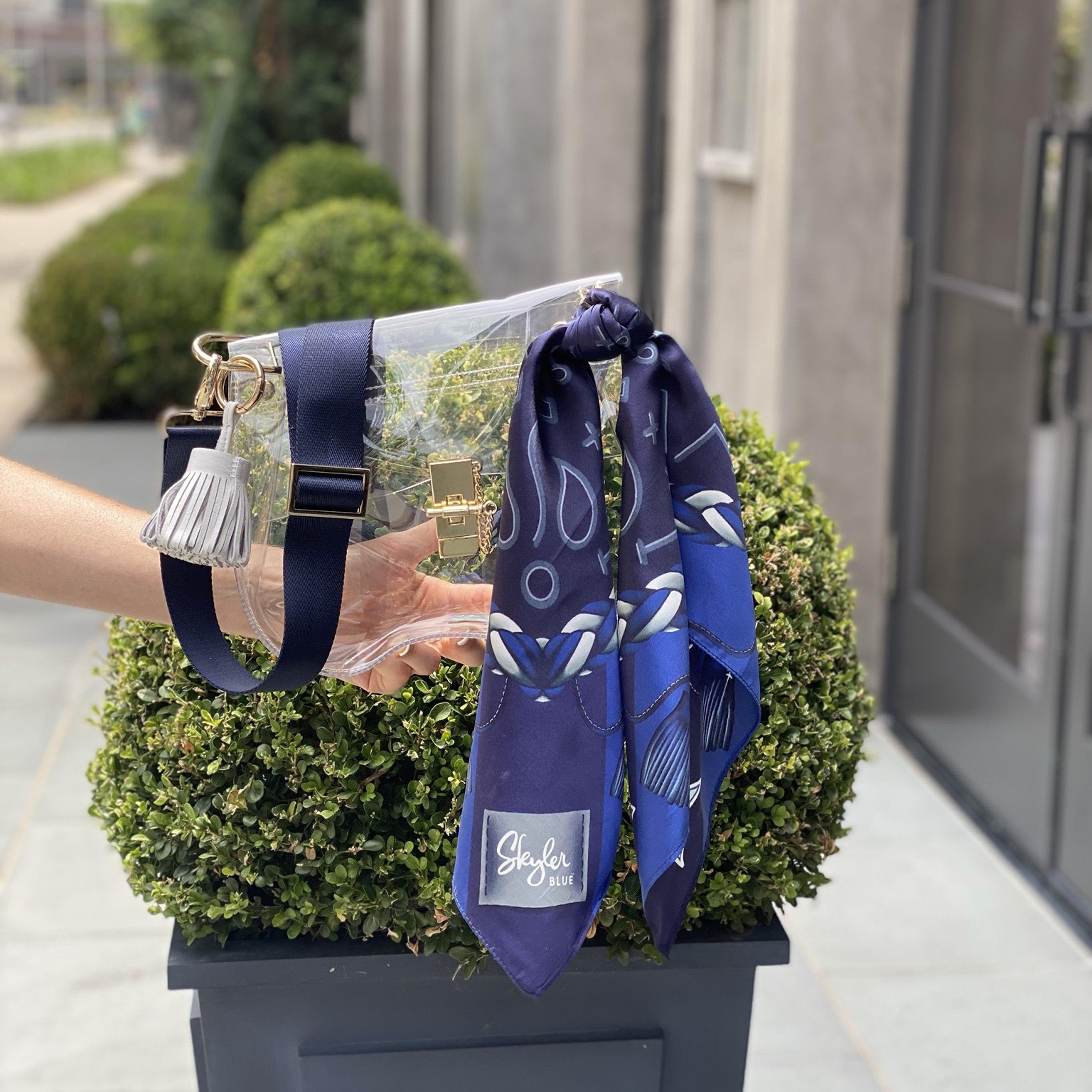 Skyler Blue’s The Dallas 001 Medium Saddle Clear Bag stadium approved clear bag / clear purse including adjustable, nylon webbing shoulder or crossbody strap with herringbone weave and gold hardware, 60-centimeter 100% silk twill scarf, and 100% genuine leather tassel.