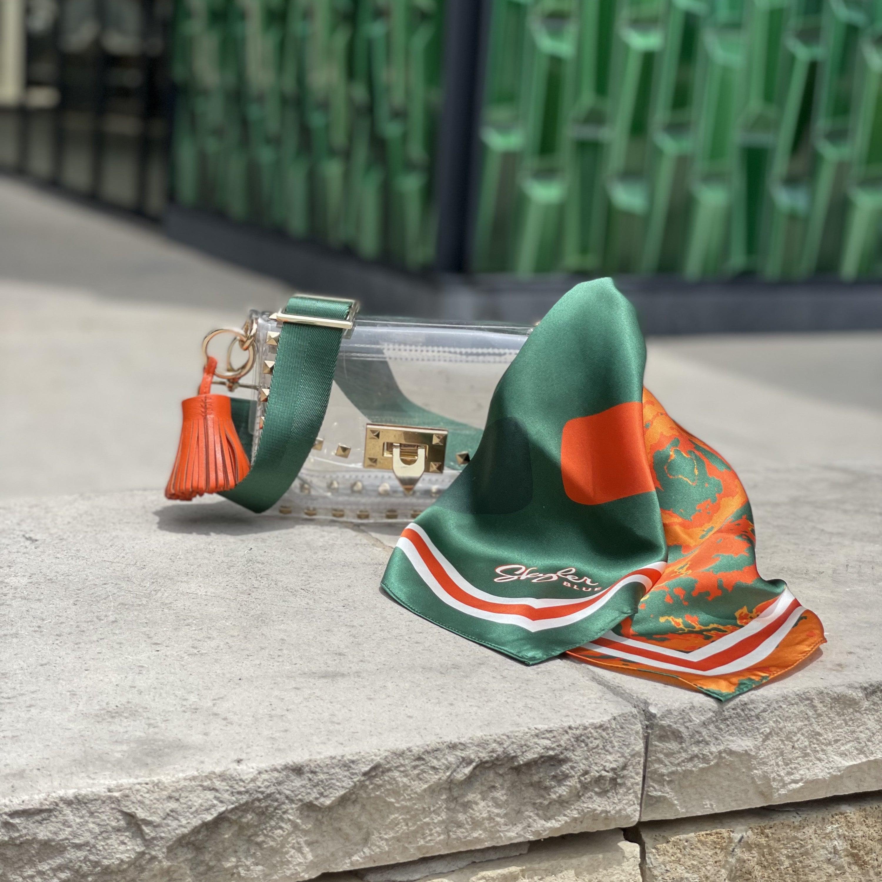 Skyler Blue’s The Coral Gables Small Studded Clear Bag stadium approved clear bag / clear purse including adjustable, nylon webbing shoulder or crossbody strap with herringbone weave and gold hardware, 60-centimeter 100% silk twill scarf, and 100% genuine leather tassel.