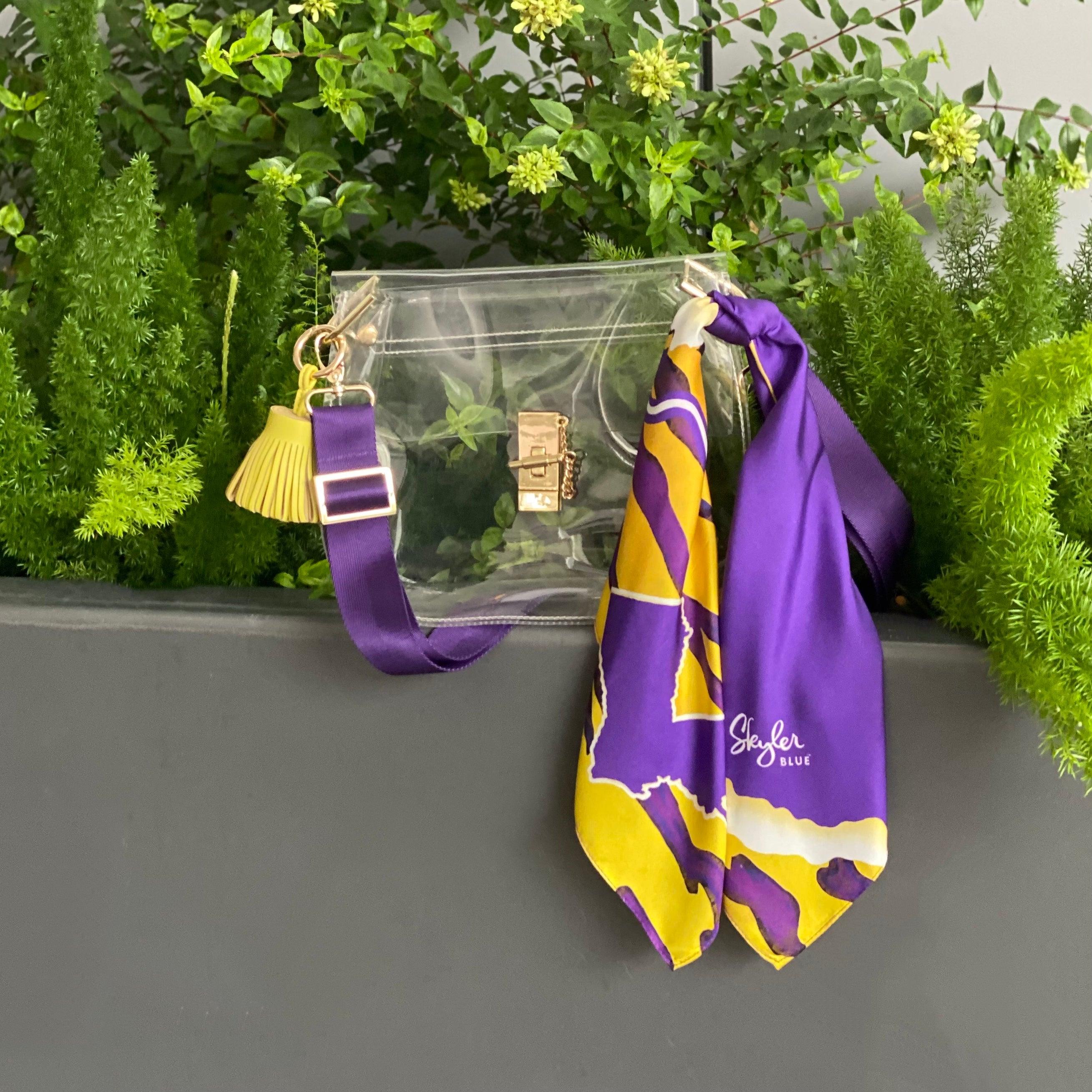 Skyler Blue’s The Baton Rouge Medium Saddle Clear Bag stadium approved clear bag / clear purse including adjustable, nylon webbing shoulder or crossbody strap with herringbone weave and gold hardware, 60-centimeter 100% silk twill scarf, and 100% genuine leather tassel.