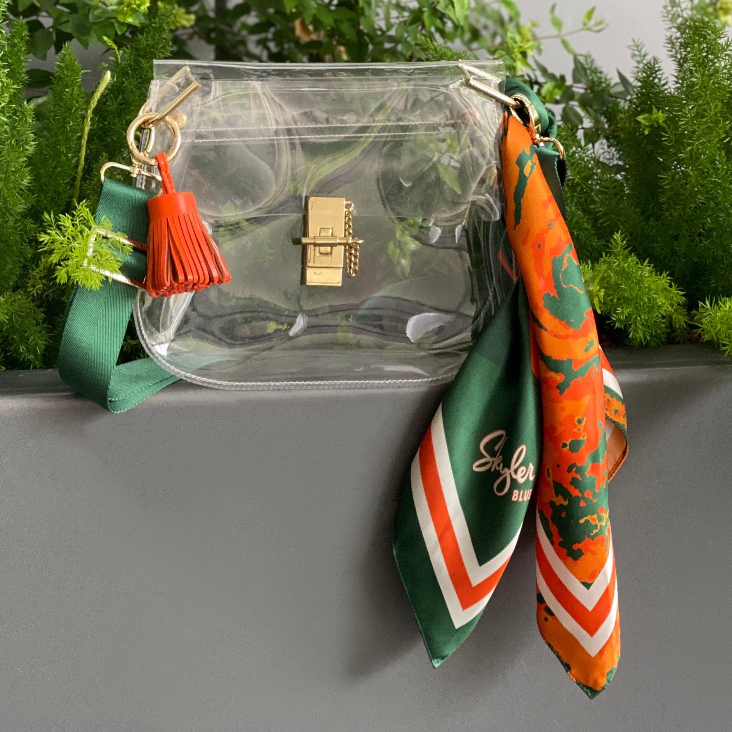 Skyler Blue’s The Coral Gables Medium Saddle Clear Bag stadium approved clear bag / clear purse including adjustable, nylon webbing shoulder or crossbody strap with herringbone weave and gold hardware, 60-centimeter 100% silk twill scarf, and 100% genuine leather tassel.