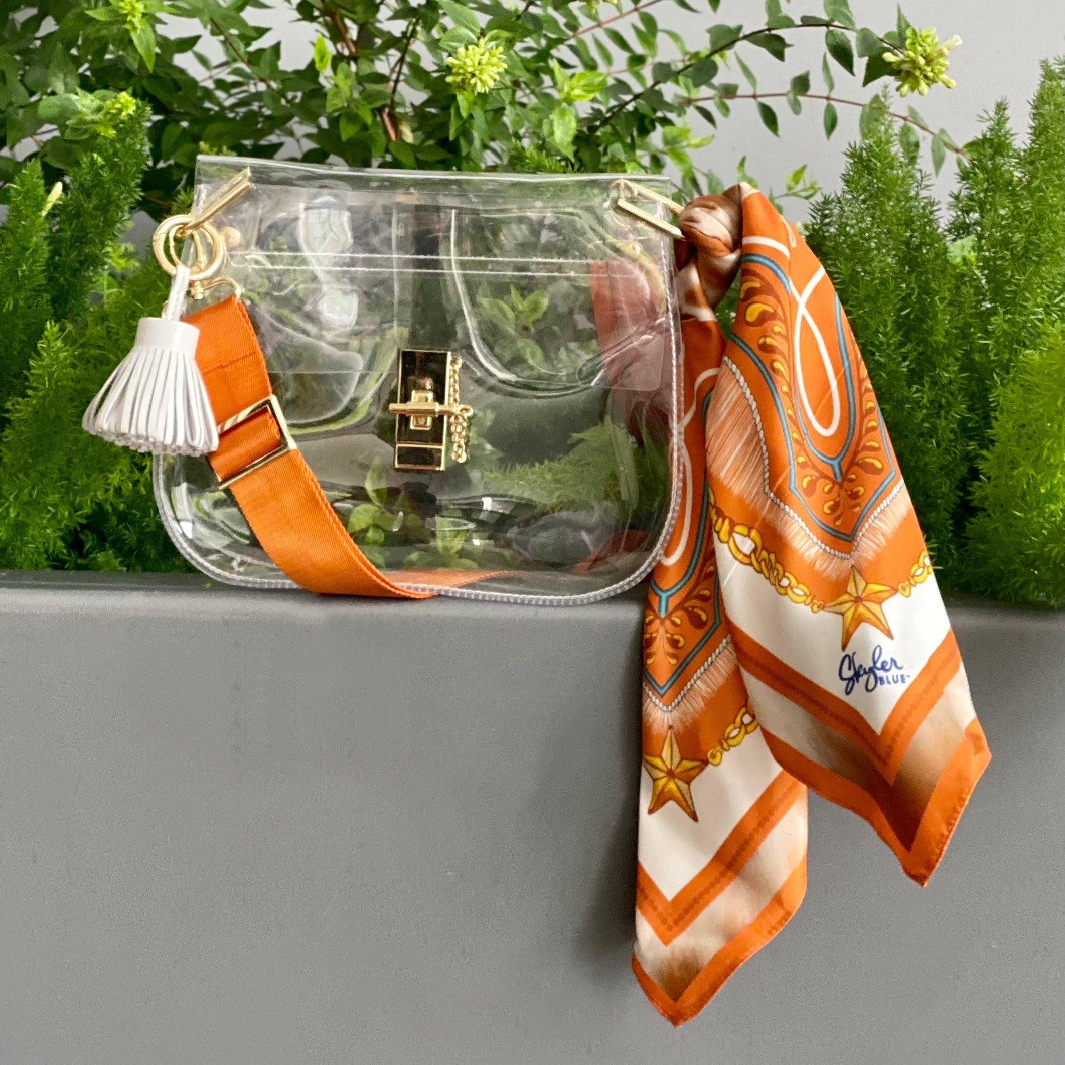 Skyler Blue’s The Austin 001 Medium Saddle Clear Bag stadium approved clear bag / clear purse including adjustable, nylon webbing shoulder or crossbody strap with herringbone weave and gold hardware, 60-centimeter 100% silk twill scarf, and 100% genuine leather tassel.
