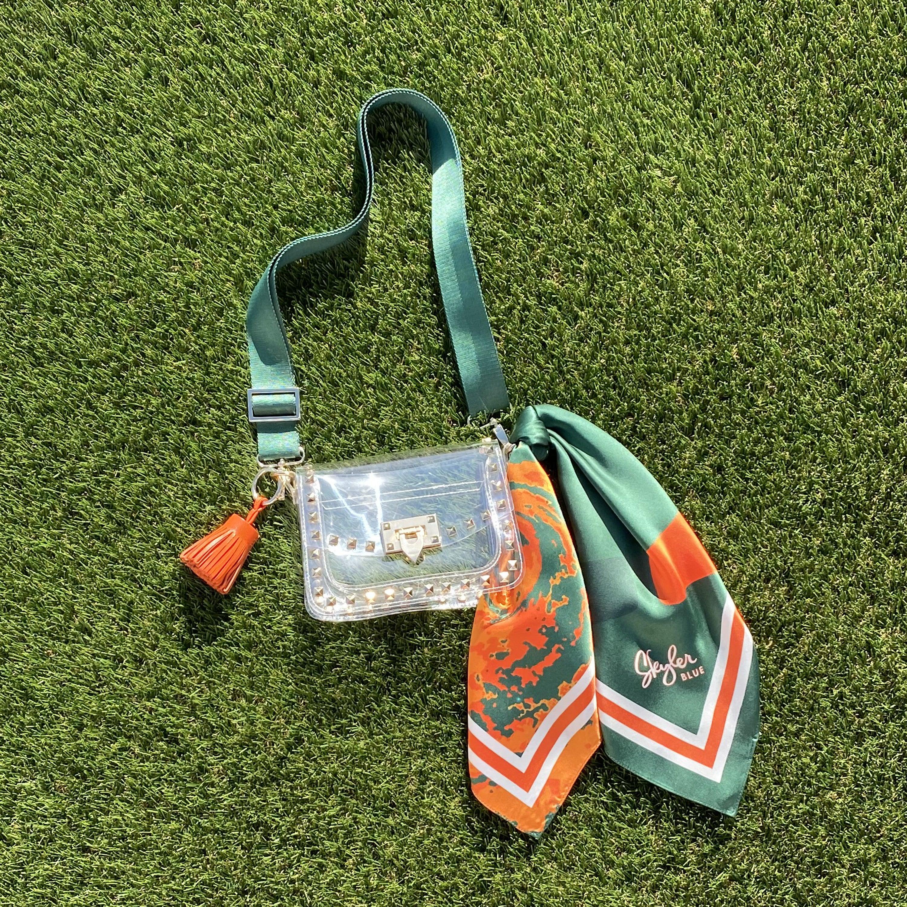 Skyler Blue’s The Coral Gables Small Studded Clear Bag stadium approved clear bag / clear purse including adjustable, nylon webbing shoulder or crossbody strap with herringbone weave and gold hardware, 60-centimeter 100% silk twill scarf, and 100% genuine leather tassel.