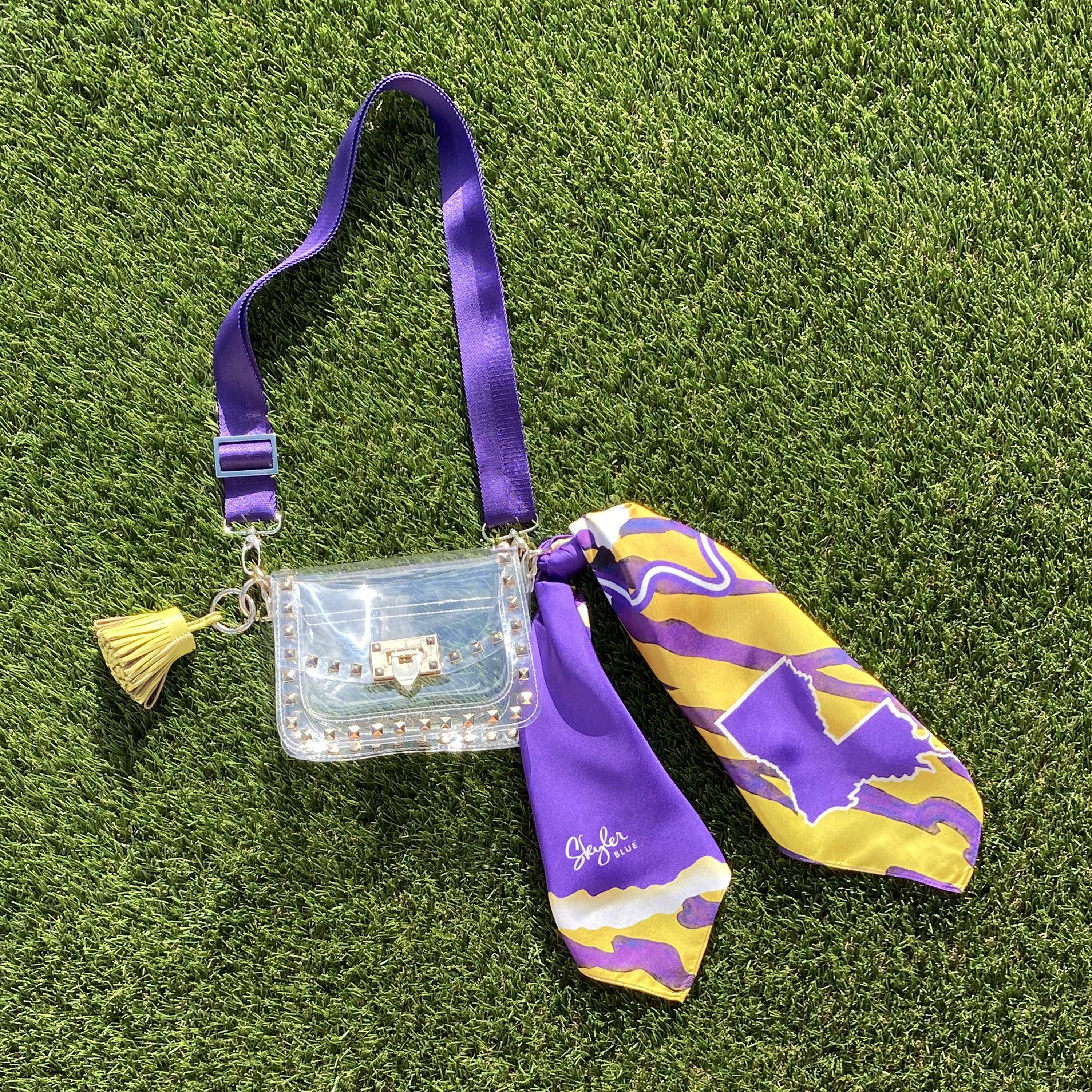 Skyler Blue’s The Baton Rouge Small Studded Clear Bag stadium approved clear bag / clear purse including adjustable, nylon webbing shoulder or crossbody strap with herringbone weave and gold hardware, 60-centimeter 100% silk twill scarf, and 100% genuine leather tassel.