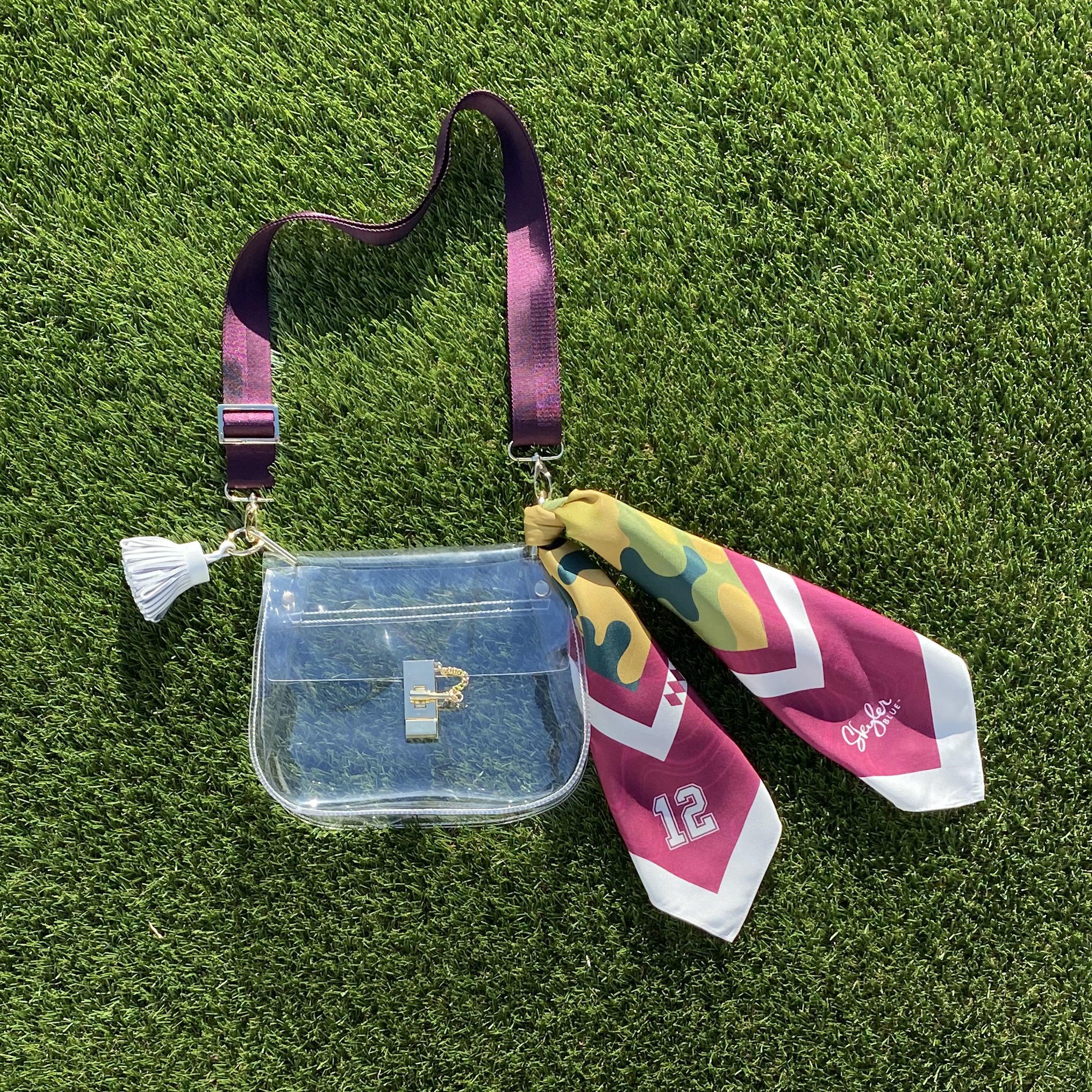 Skyler Blue’s The College Station Medium Saddle Clear Bag stadium approved clear bag / clear purse including adjustable, nylon webbing shoulder or crossbody strap with herringbone weave and gold hardware, 60-centimeter 100% silk twill scarf, and 100% genuine leather tassel.