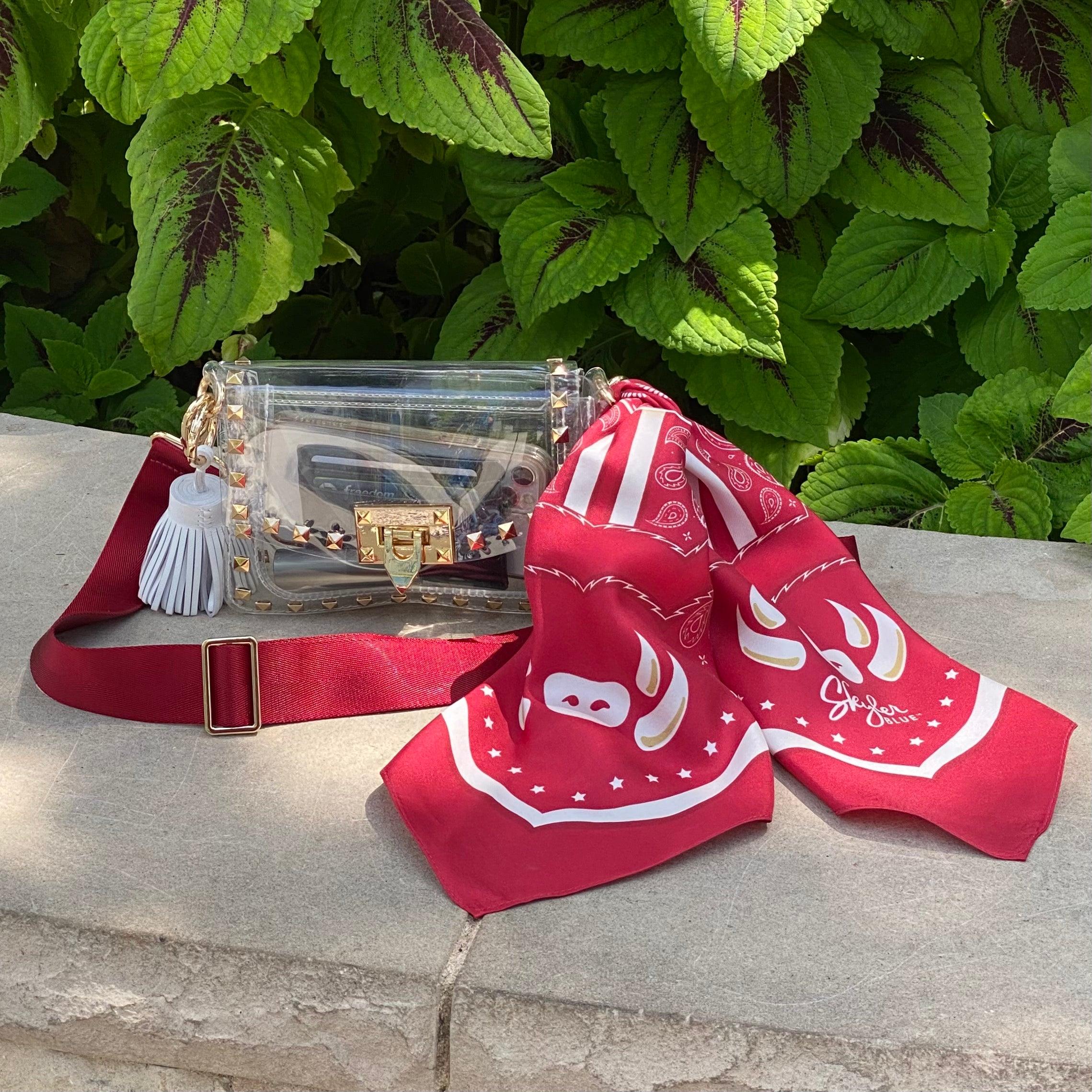 Skyler Blue’s The Fayetteville Small Studded Clear Bag stadium approved clear bag / clear purse including adjustable, nylon webbing shoulder or crossbody strap with herringbone weave and gold hardware, 60-centimeter 100% silk twill scarf, and 100% genuine leather tassel.