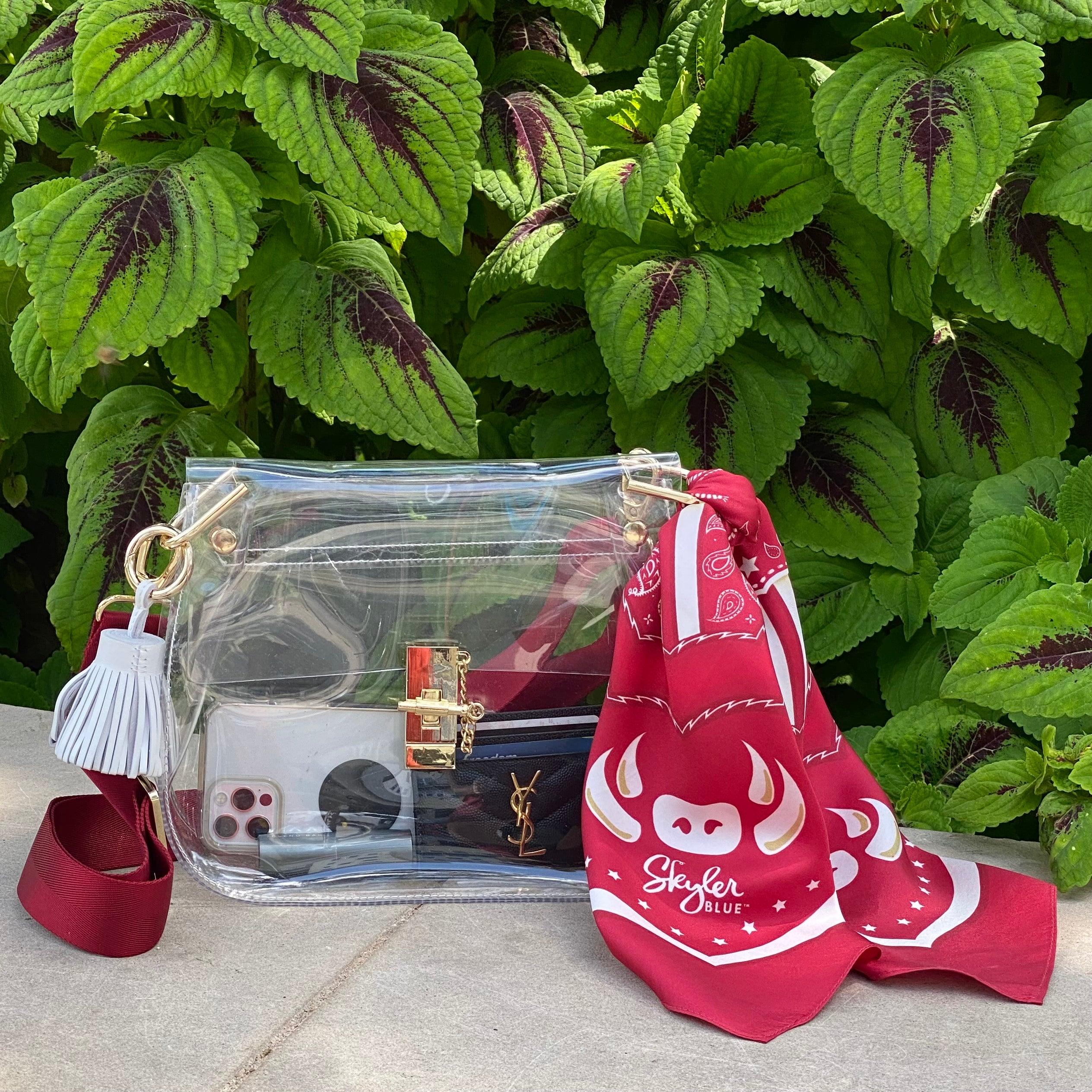 Skyler Blue’s The Fayetteville Medium Saddle Clear Bag stadium approved clear bag / clear purse including adjustable, nylon webbing shoulder or crossbody strap with herringbone weave and gold hardware, 60-centimeter 100% silk twill scarf, and 100% genuine leather tassel.