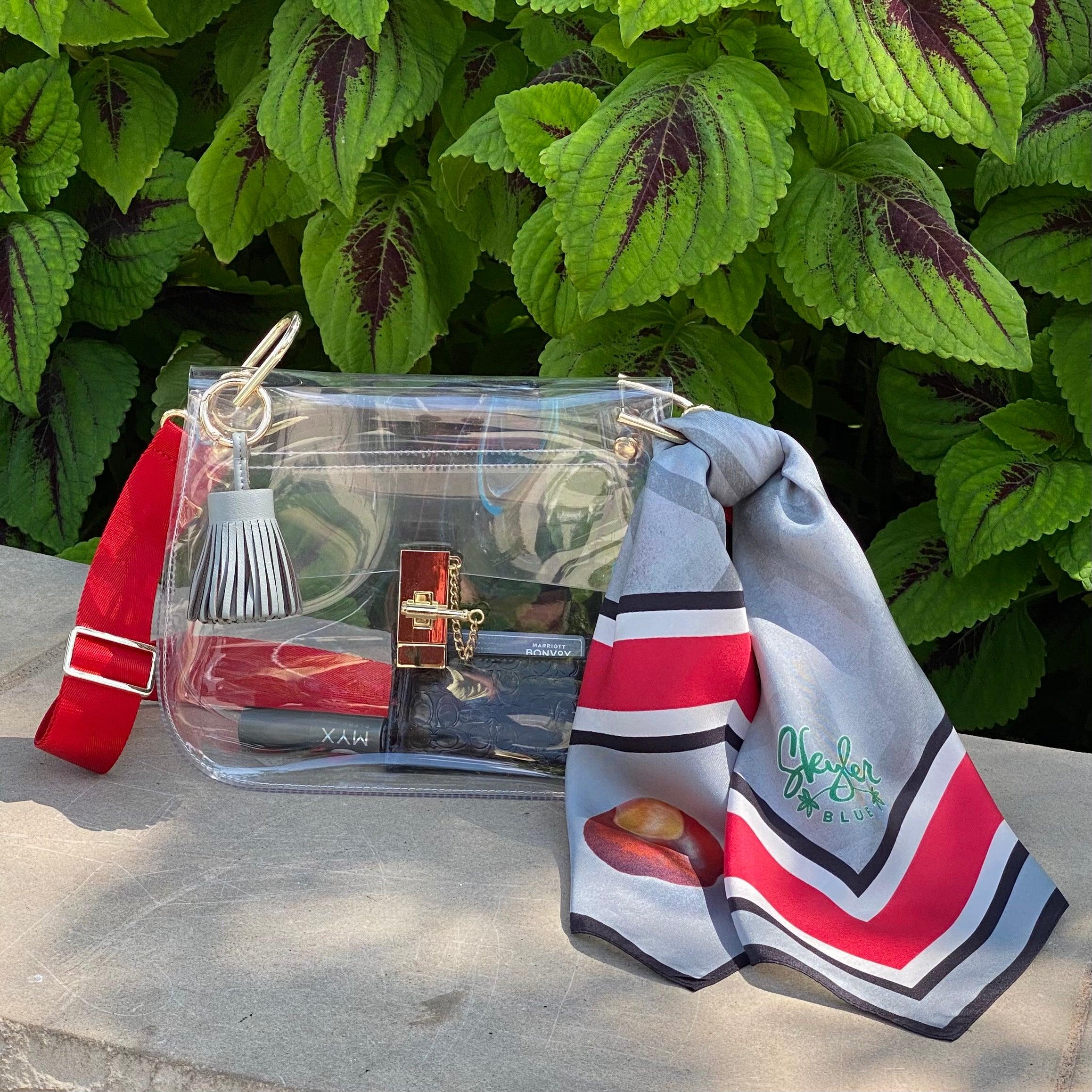 Skyler Blue’s The Columbus Medium Saddle Clear Bag stadium approved clear bag / clear purse including adjustable, nylon webbing shoulder or crossbody strap with herringbone weave and gold hardware, 60-centimeter 100% silk twill scarf, and 100% genuine leather tassel.