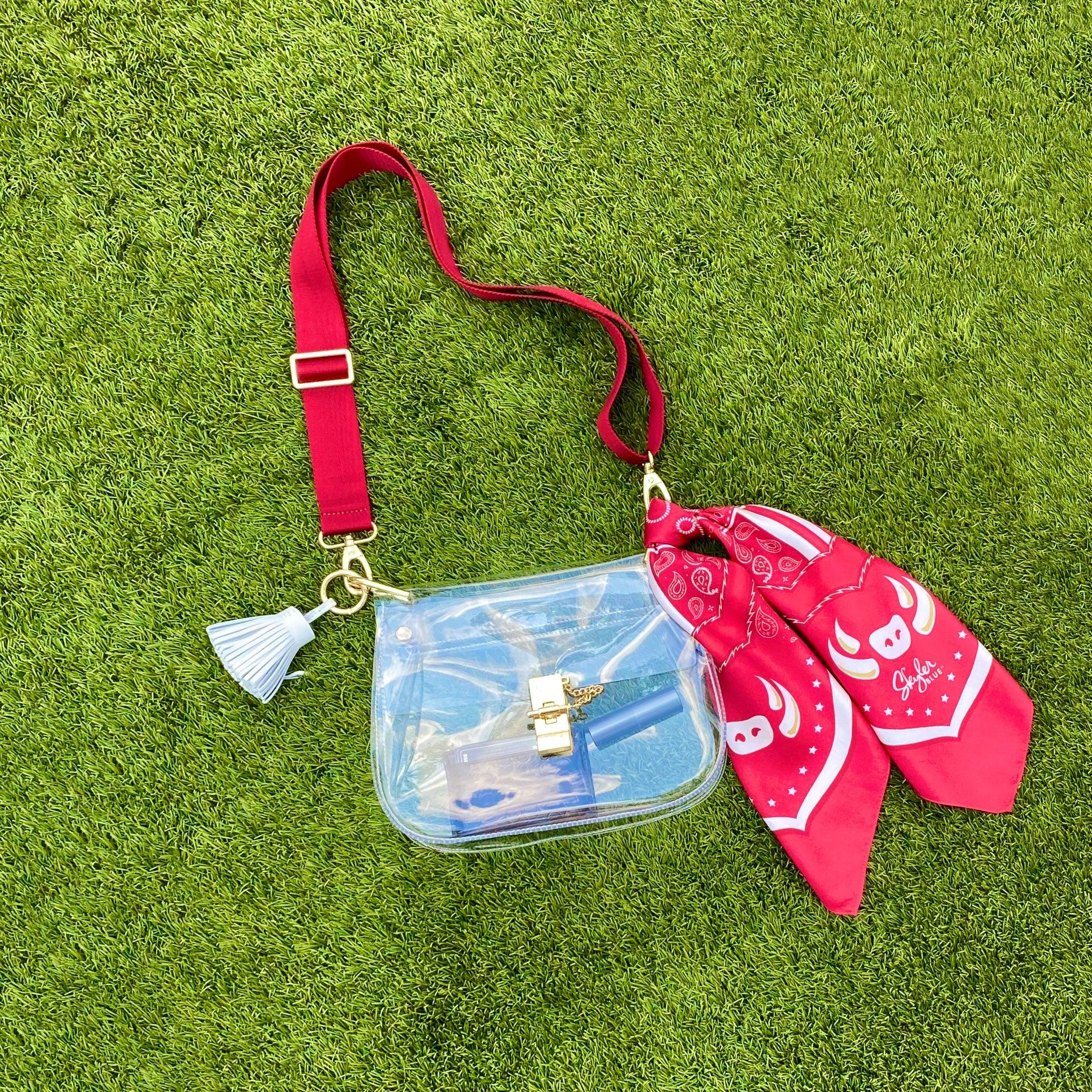 Skyler Blue’s The Fayetteville Medium Saddle Clear Bag stadium approved clear bag / clear purse including adjustable, nylon webbing shoulder or crossbody strap with herringbone weave and gold hardware, 60-centimeter 100% silk twill scarf, and 100% genuine leather tassel.