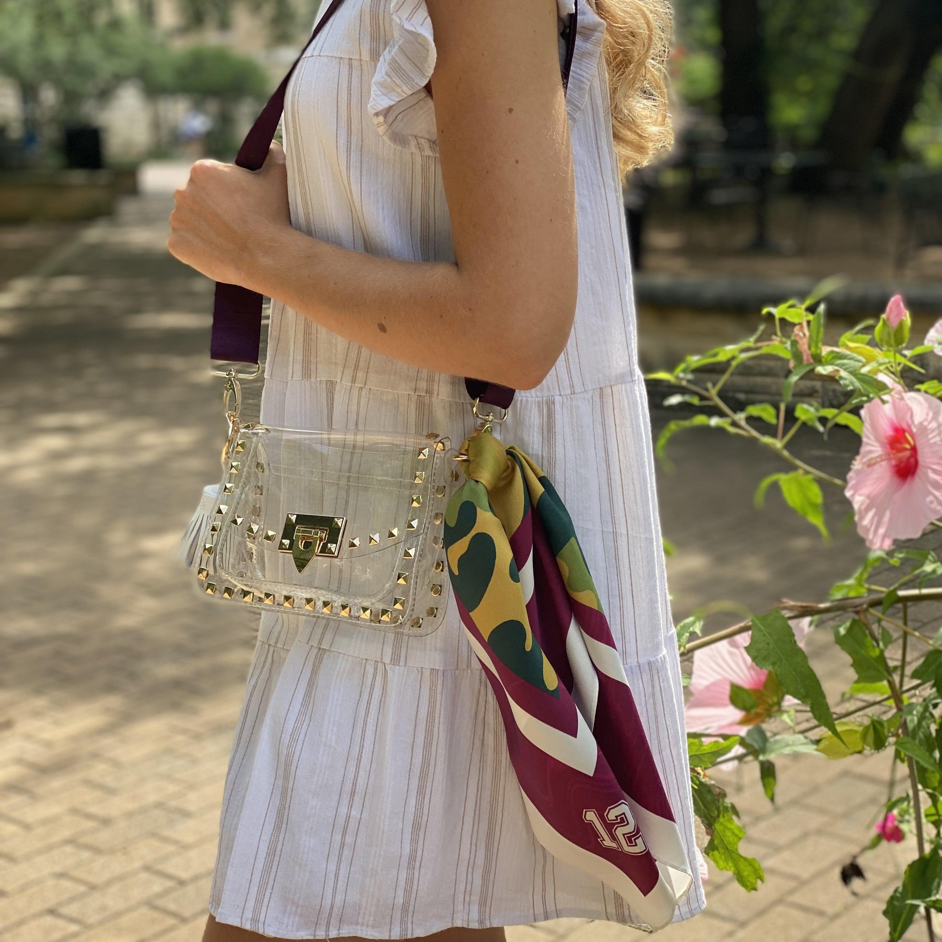 Model wearing Skyler Blue’s The College Station Small Studded Clear Bag stadium approved clear bag / clear purse including adjustable, nylon webbing shoulder or crossbody strap with herringbone weave and gold hardware, 60-centimeter 100% silk twill scarf, and 100% genuine leather tassel.