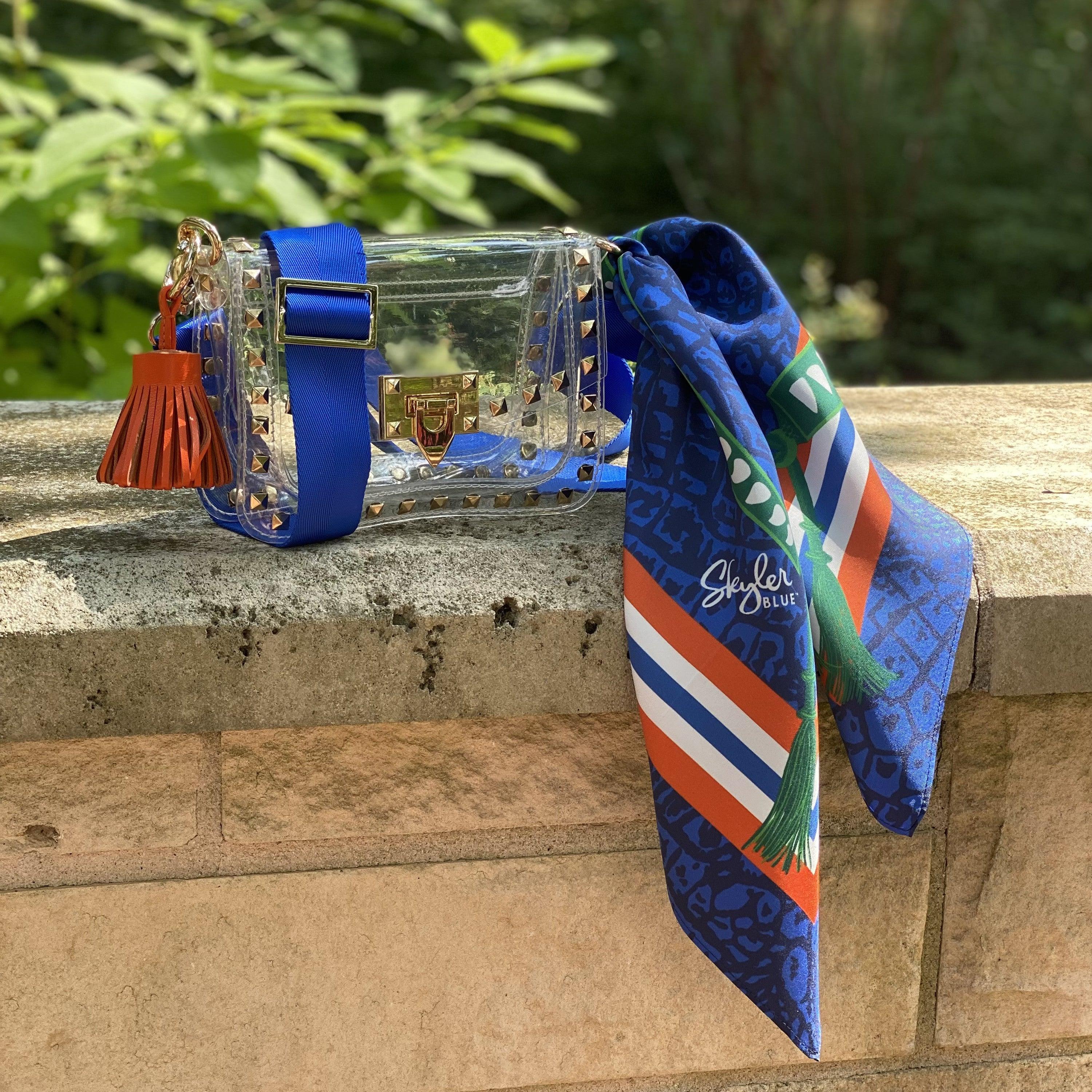 Skyler Blue’s The Gainesville Small Studded Clear Bag stadium approved clear bag / clear purse including adjustable, nylon webbing shoulder or crossbody strap with herringbone weave and gold hardware, 60-centimeter 100% silk twill scarf, and 100% genuine leather tassel.