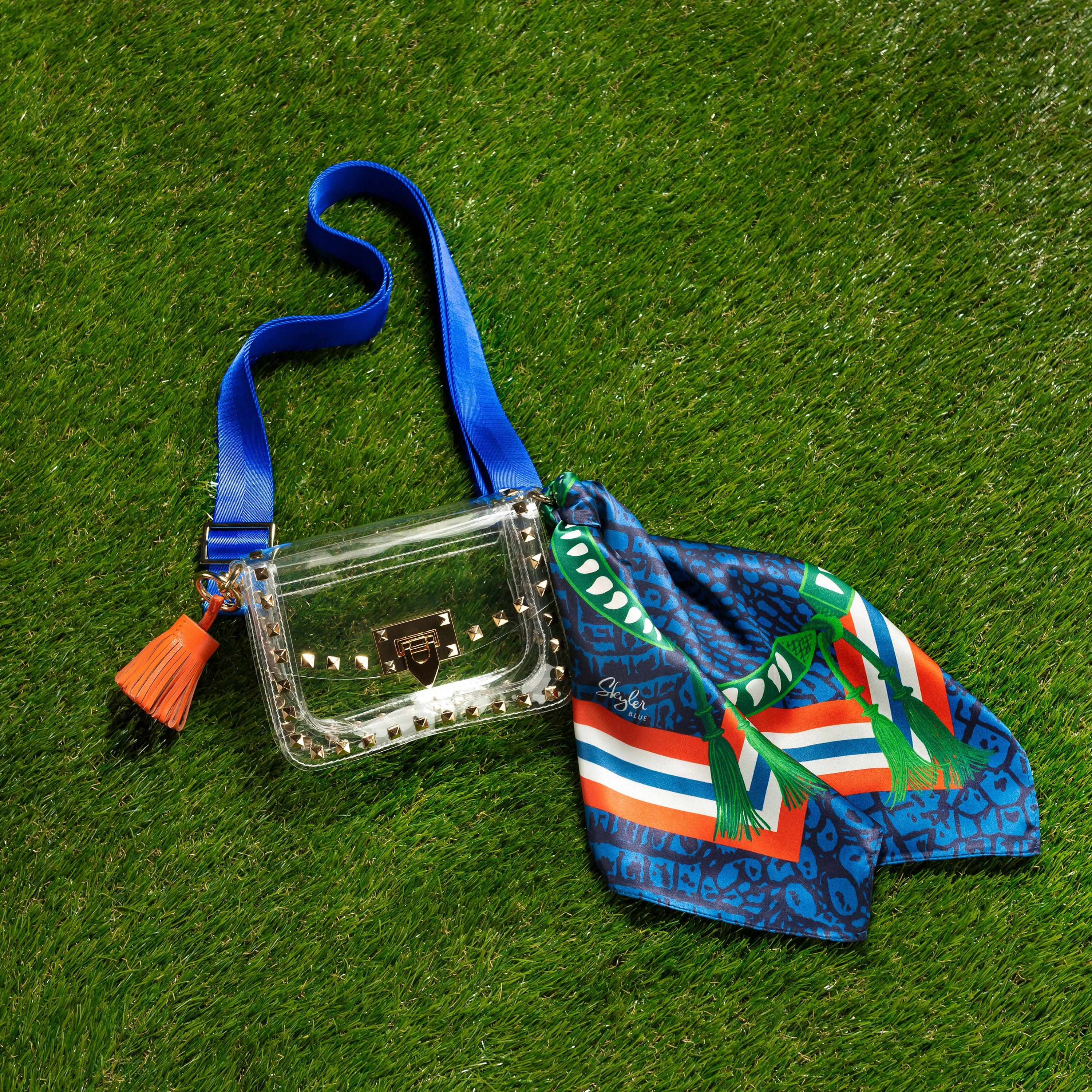 Skyler Blue’s The Gainesville Small Studded Clear Bag stadium approved clear bag / clear purse including adjustable, nylon webbing shoulder or crossbody strap with herringbone weave and gold hardware, 60-centimeter 100% silk twill scarf, and 100% genuine leather tassel.