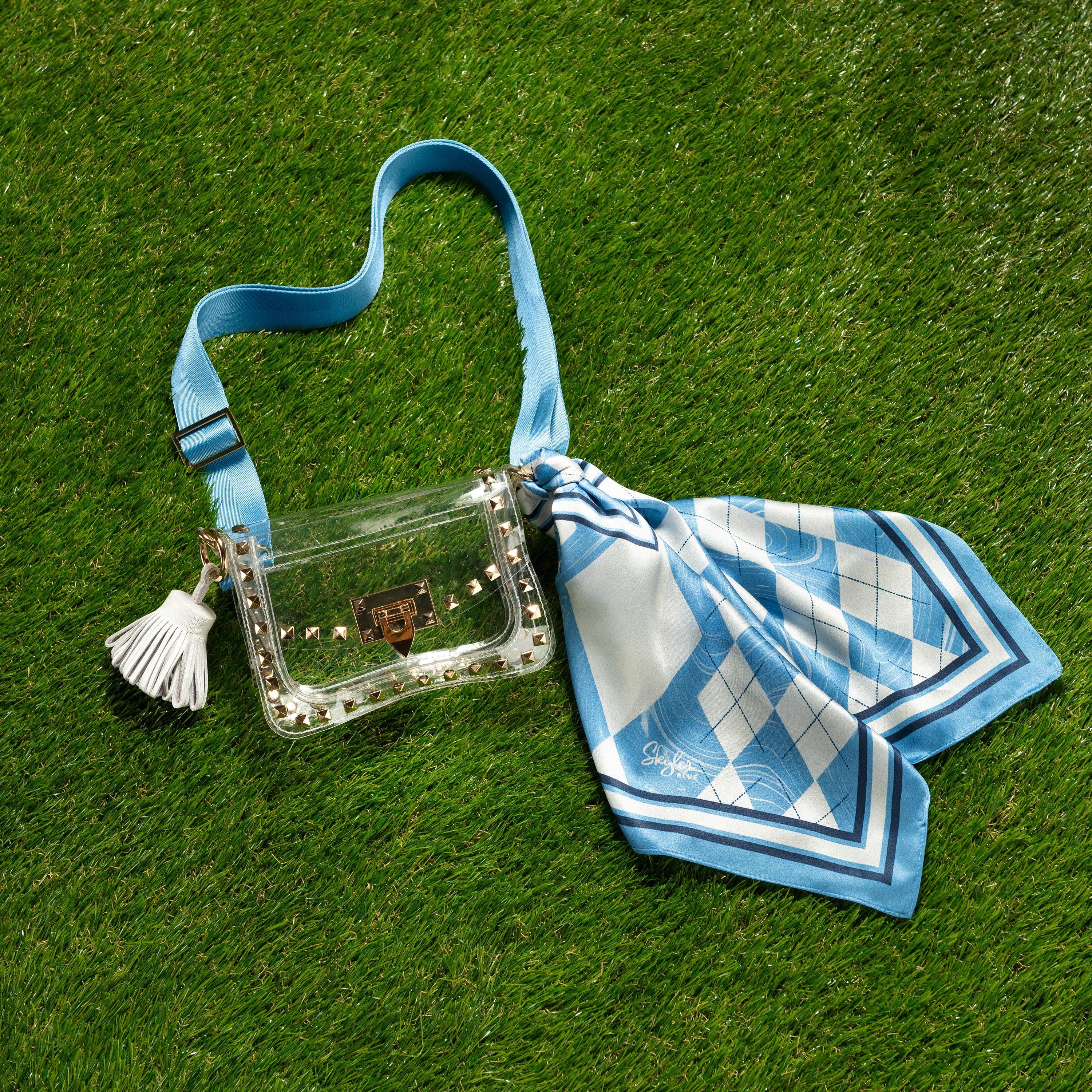 Skyler Blue’s The Chapel Hill Small Studded Clear Bag stadium approved clear bag / clear purse including adjustable, nylon webbing shoulder or crossbody strap with herringbone weave and gold hardware, 60-centimeter 100% silk twill scarf, and 100% genuine leather tassel.