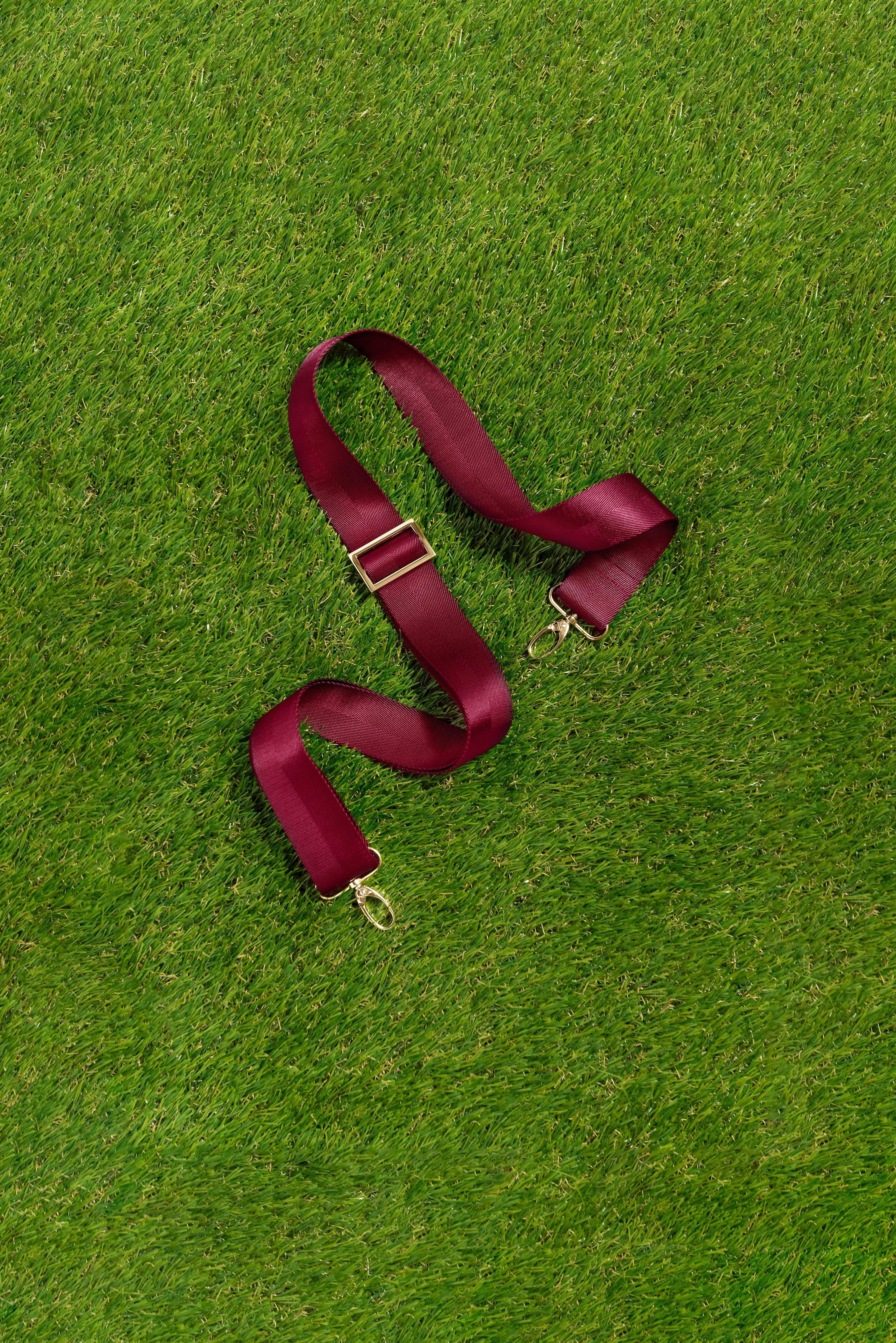 Skyler Blue’s adjustable, nylon webbing maroon shoulder or crossbody strap with herringbone weave and gold hardware.