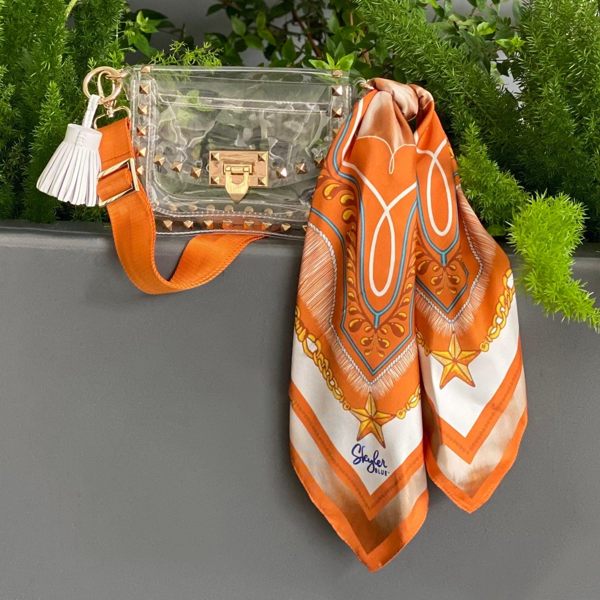 Skyler Blue’s The Austin 001 Small Studded Clear Bag stadium approved clear bag / clear purse including adjustable, nylon webbing shoulder or crossbody strap with herringbone weave and gold hardware, 60-centimeter 100% silk twill scarf, and 100% genuine leather tassel.