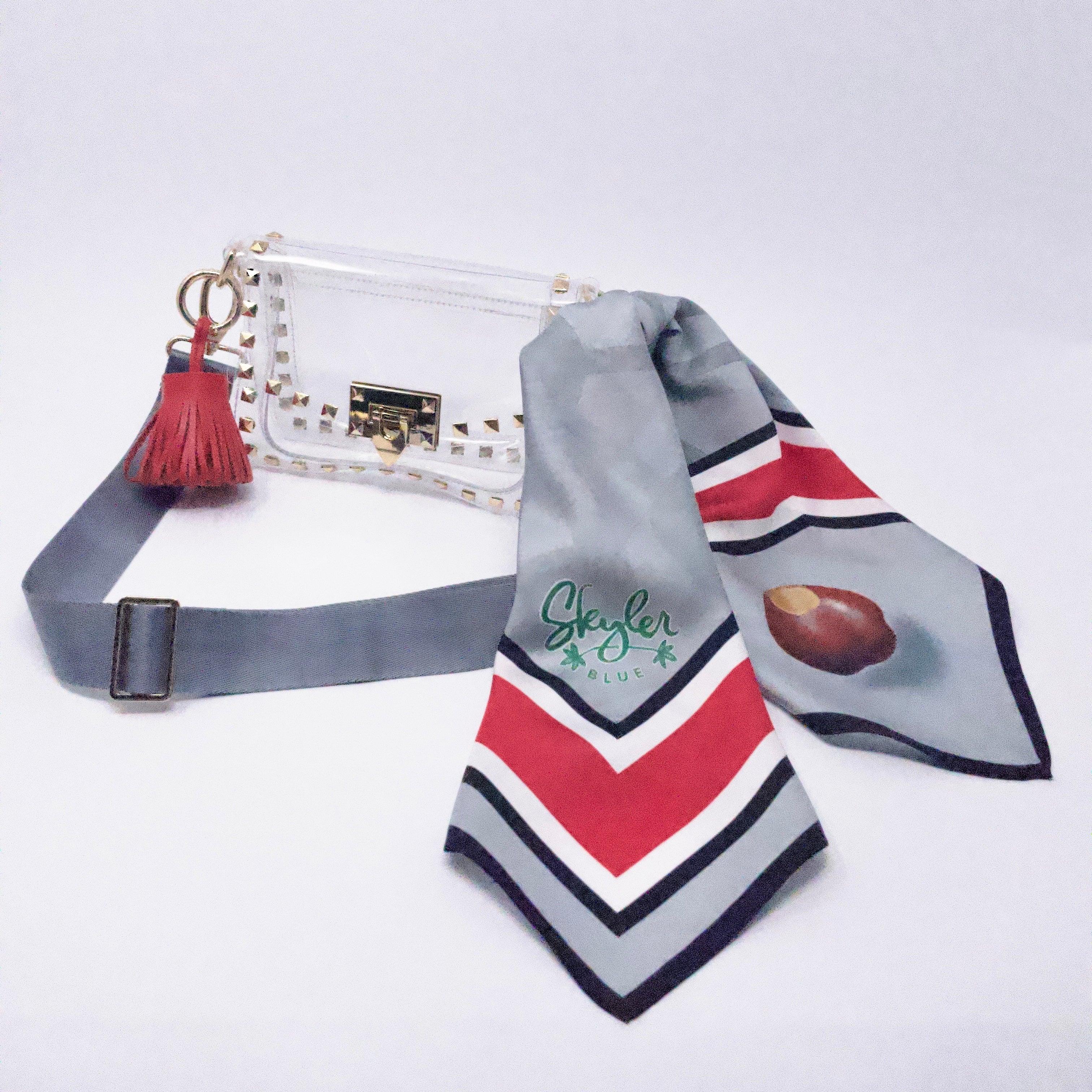 Skyler Blue’s The Columbus Small Studded Clear Bag stadium approved clear bag / clear purse including adjustable, nylon webbing shoulder or crossbody strap with herringbone weave and gold hardware, 60-centimeter 100% silk twill scarf, and 100% genuine leather tassel.