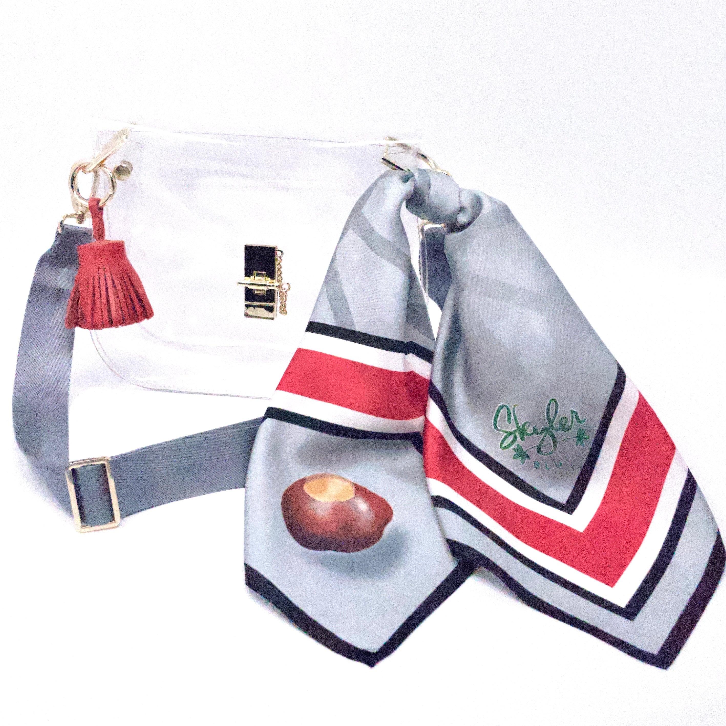Skyler Blue’s The Columbus Medium Saddle Clear Bag stadium approved clear bag / clear purse including adjustable, nylon webbing shoulder or crossbody strap with herringbone weave and gold hardware, 60-centimeter 100% silk twill scarf, and 100% genuine leather tassel.
