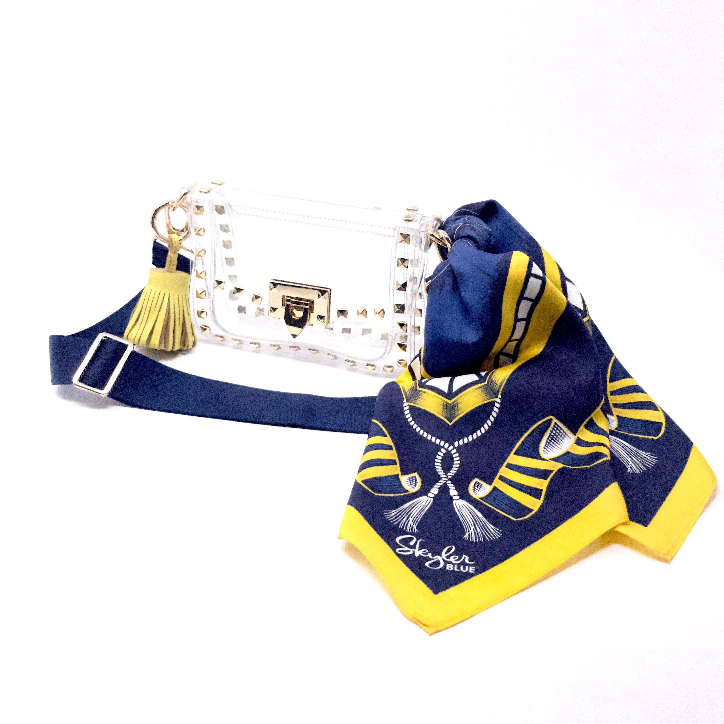 Skyler Blue’s The Ann Arbor Small Studded Clear Bag stadium approved clear bag / clear purse including adjustable, nylon webbing shoulder or crossbody strap with herringbone weave and gold hardware, 60-centimeter 100% silk twill scarf, and 100% genuine leather tassel.