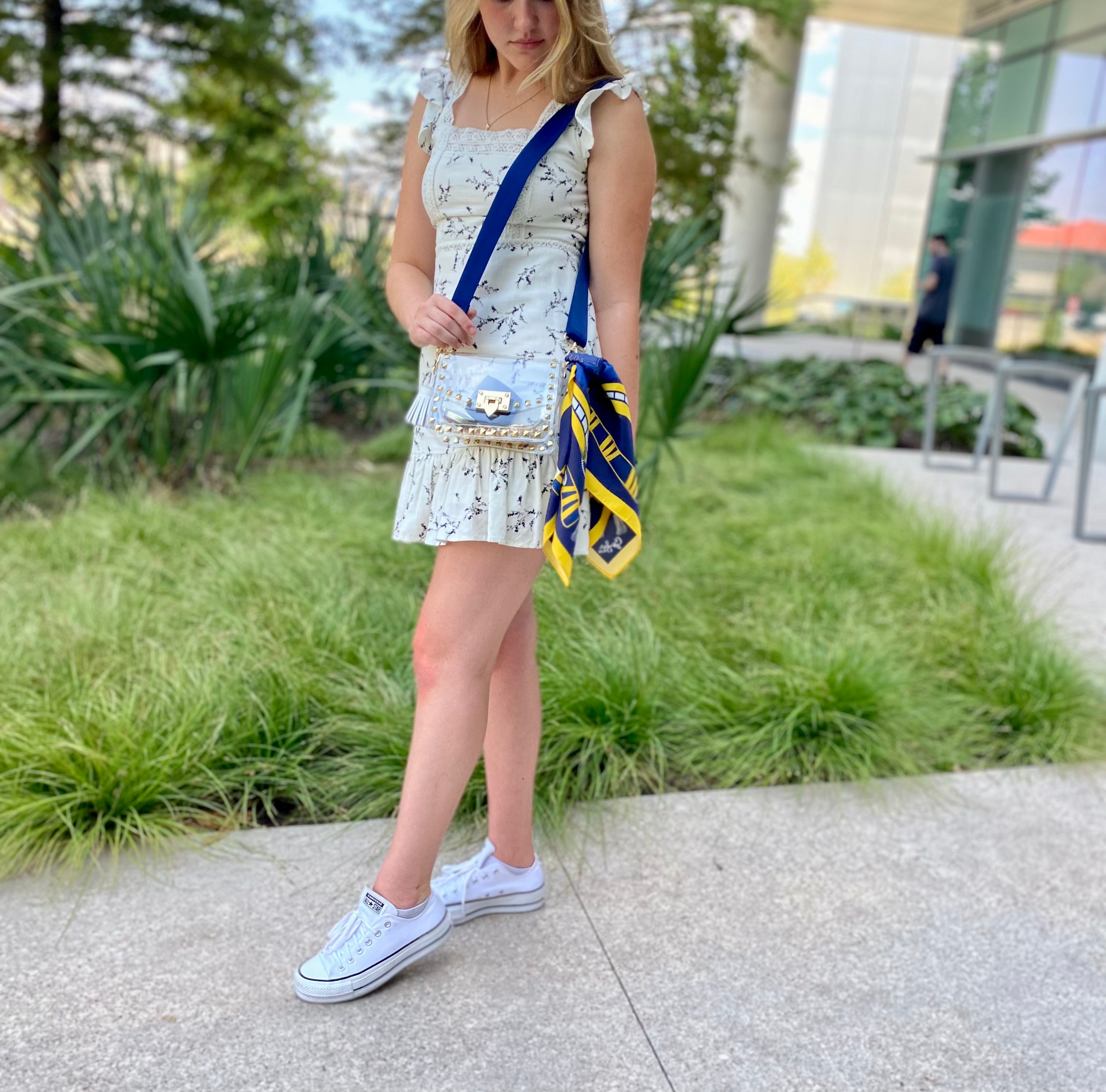 Model wearing Skyler Blue’s The Ann Arbor Small Studded Clear Bag stadium approved clear bag / clear purse including adjustable, nylon webbing shoulder or crossbody strap with herringbone weave and gold hardware, 60-centimeter 100% silk twill scarf, and 100% genuine leather tassel.