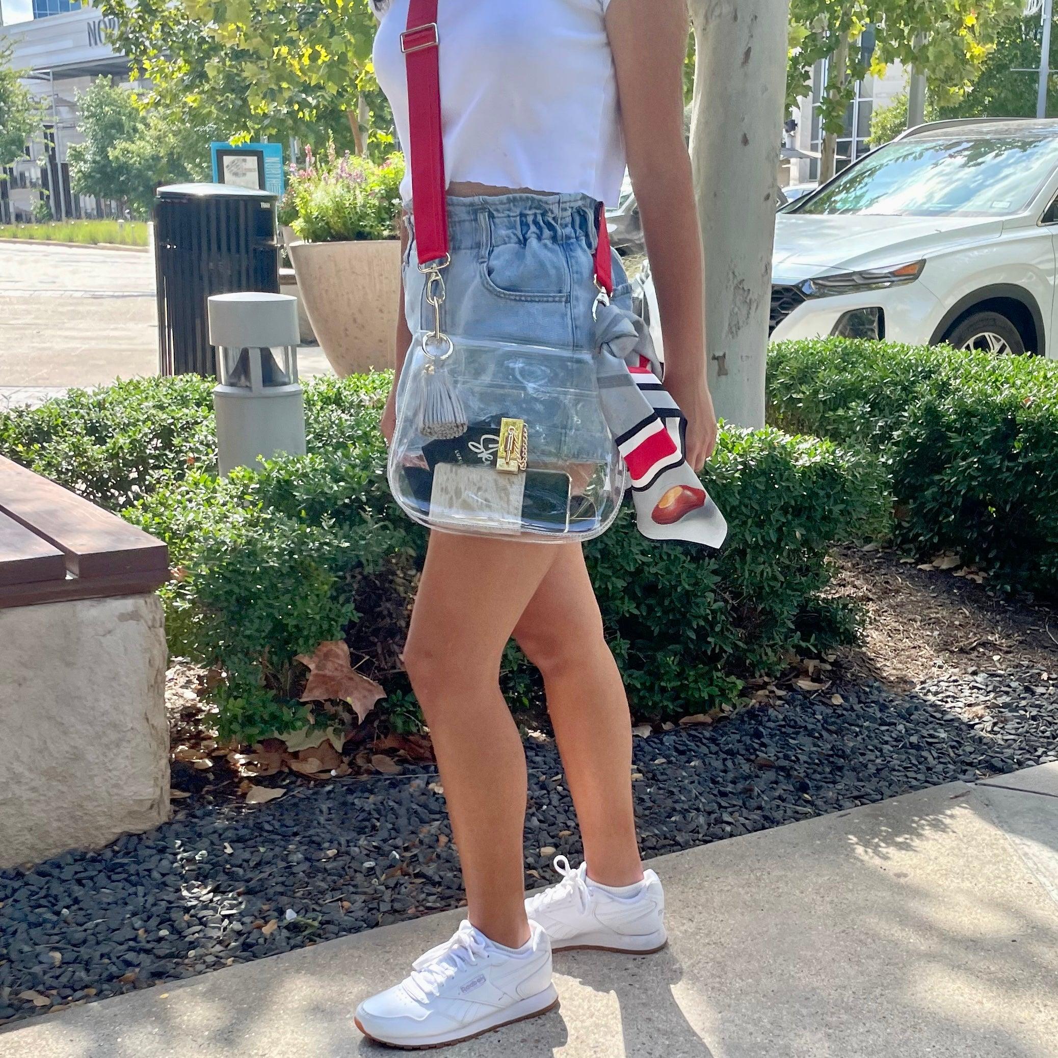 Model wearing Skyler Blue’s The Columbus Medium Saddle Clear Bag stadium approved clear bag / clear purse including adjustable, nylon webbing shoulder or crossbody strap with herringbone weave and gold hardware, 60-centimeter 100% silk twill scarf, and 100% genuine leather tassel.