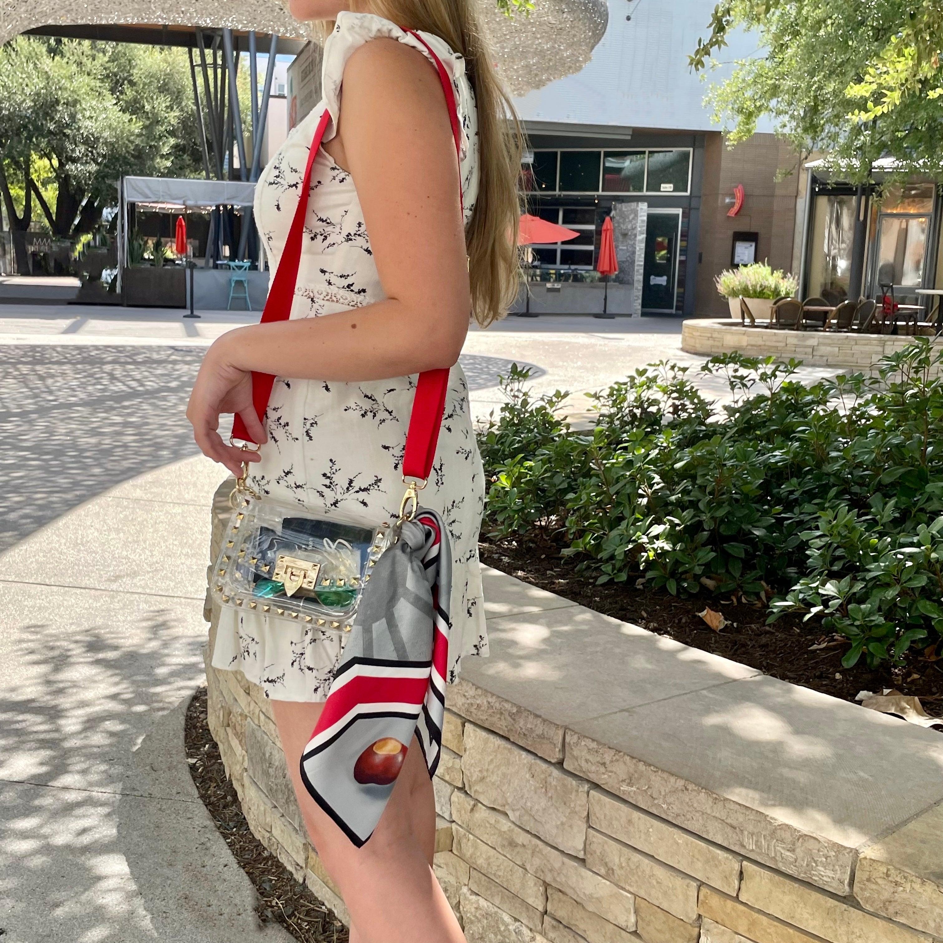 Model wearing Skyler Blue’s The Columbus Small Studded Clear Bag stadium approved clear bag / clear purse including adjustable, nylon webbing shoulder or crossbody strap with herringbone weave and gold hardware, 60-centimeter 100% silk twill scarf, and 100% genuine leather tassel.