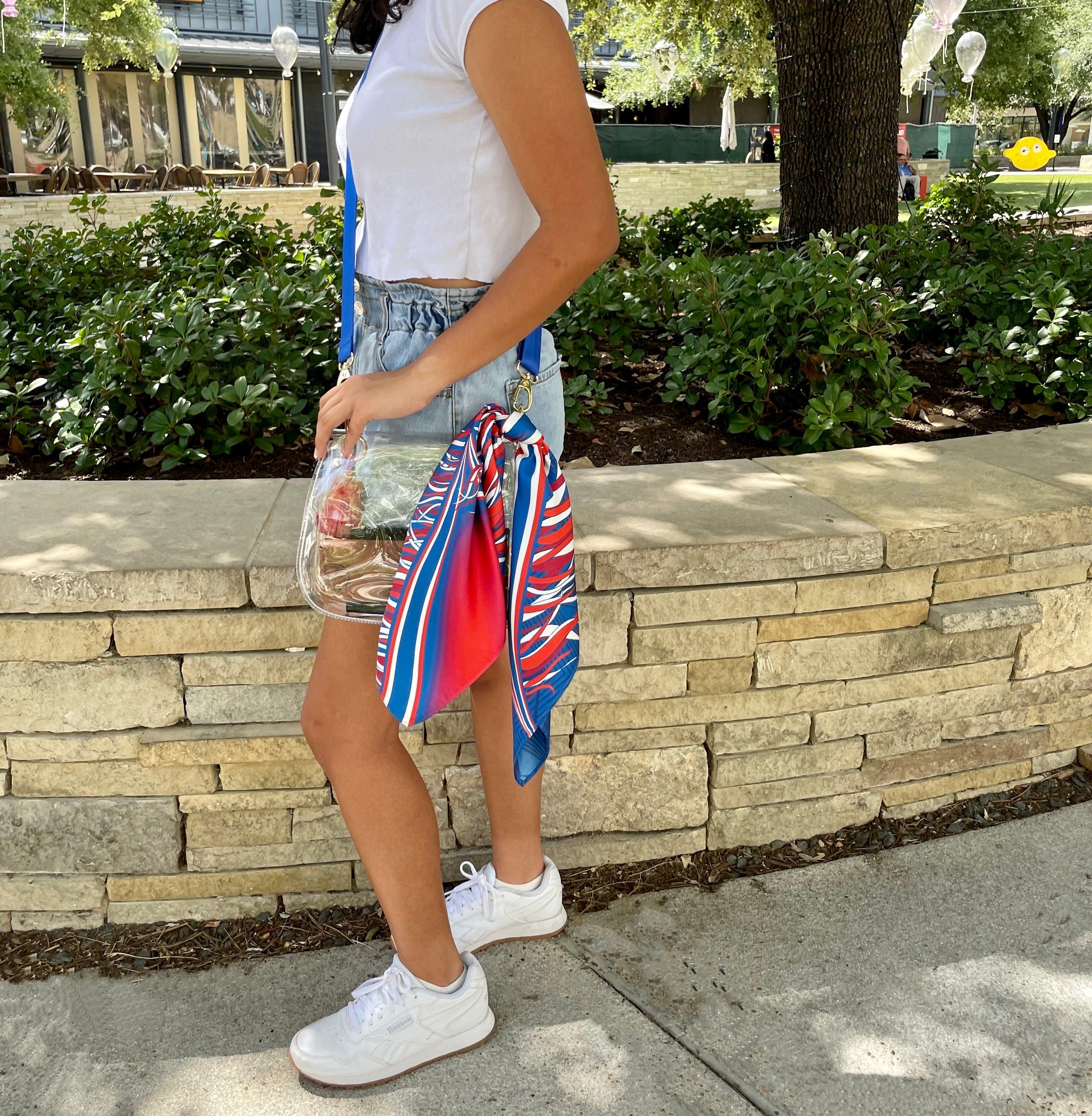 Model wearing Skyler Blue’s The Hilltop Medium Saddle Clear Bag stadium approved clear bag / clear purse including adjustable, nylon webbing shoulder or crossbody strap with herringbone weave and gold hardware, 60-centimeter 100% silk twill scarf, and 100% genuine leather tassel.