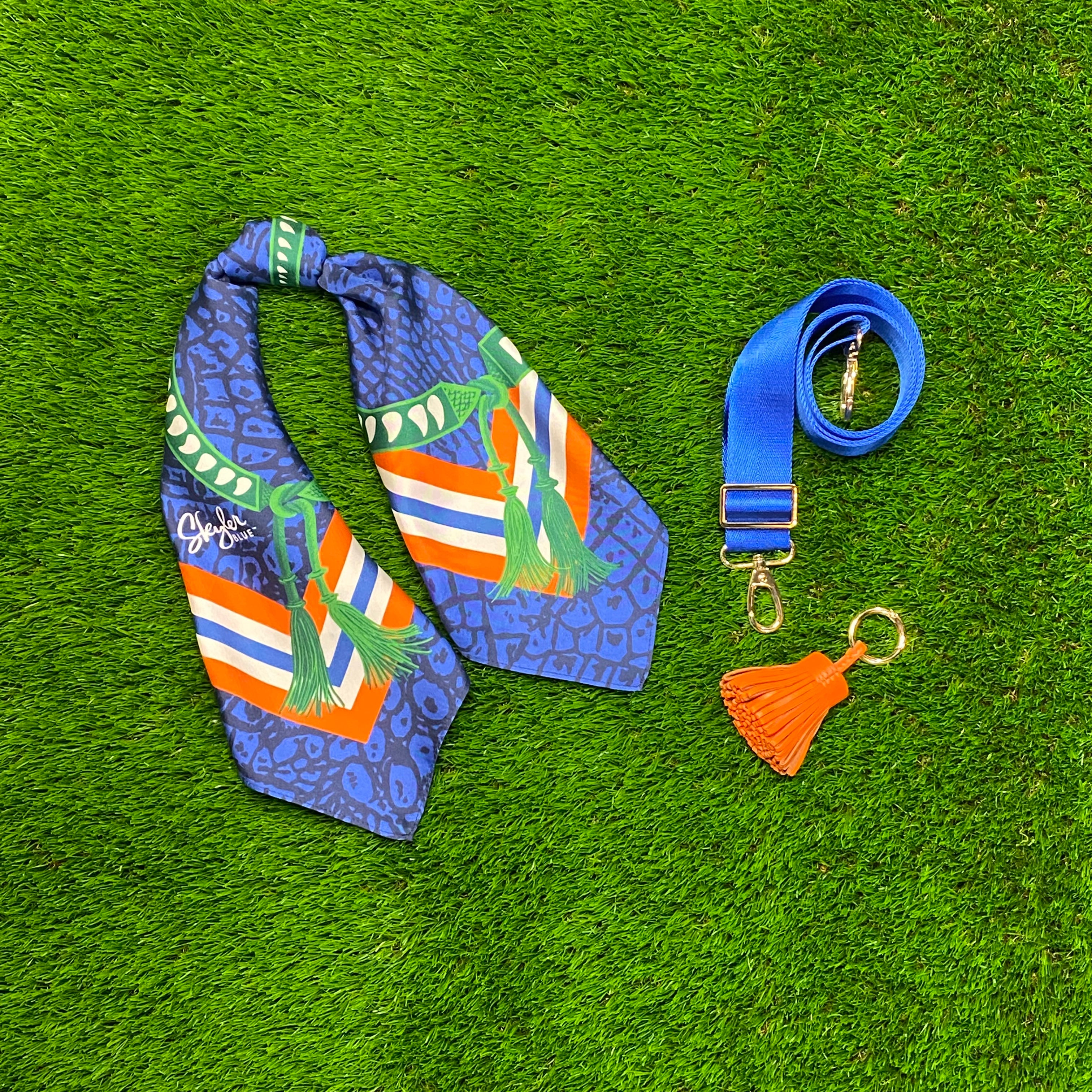 Skyler Blue’s The Gainesville Accessory Package including adjustable, nylon webbing shoulder or crossbody strap with herringbone weave and gold hardware, 60-centimeter 100% silk twill scarf, and 100% genuine leather tassel.