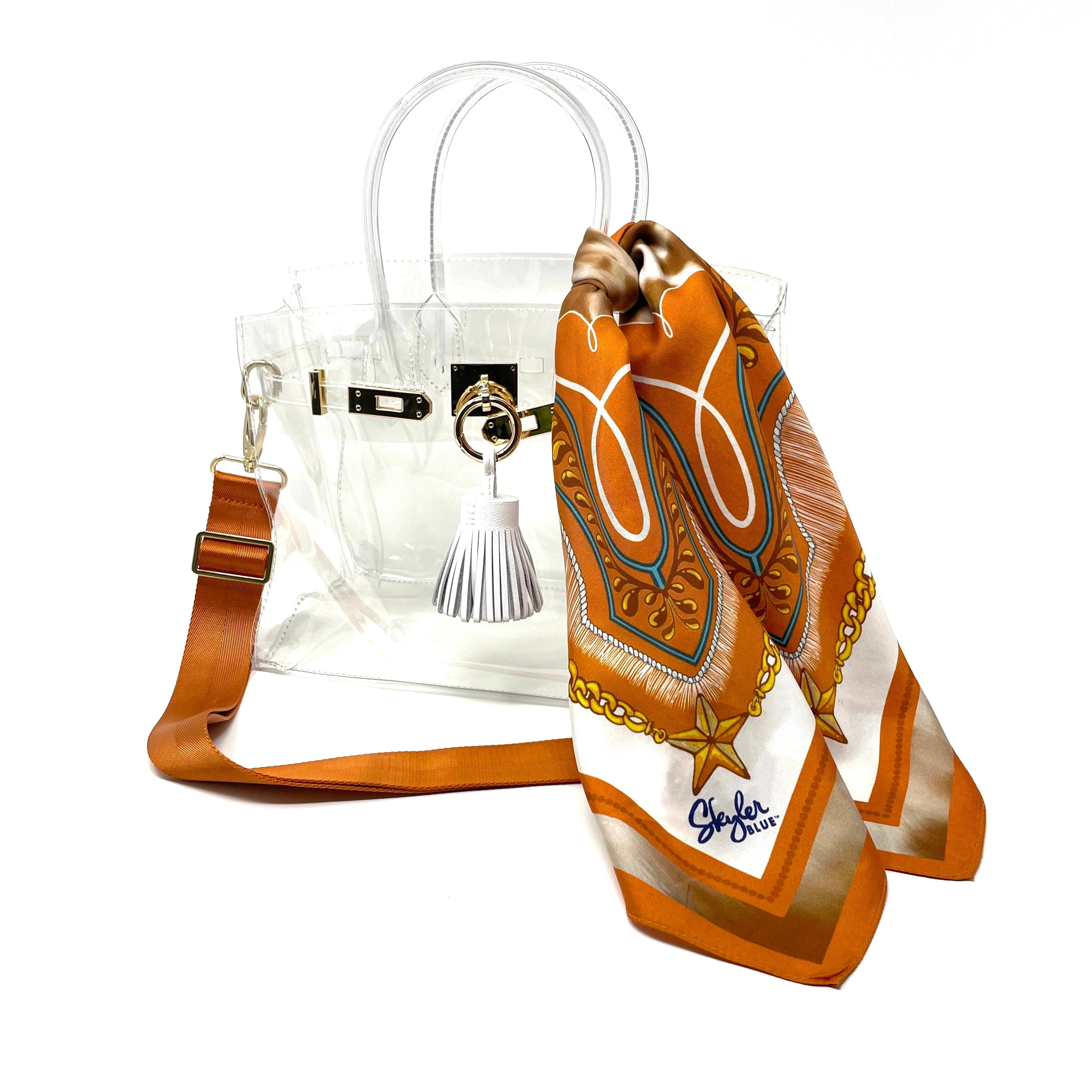 Skyler Blue’s The Austin 001 Large Clear Satchel stadium approved clear bag / clear purse including adjustable, nylon webbing shoulder or crossbody strap with herringbone weave and gold hardware, 60-centimeter 100% silk twill scarf, and 100% genuine leather tassel.