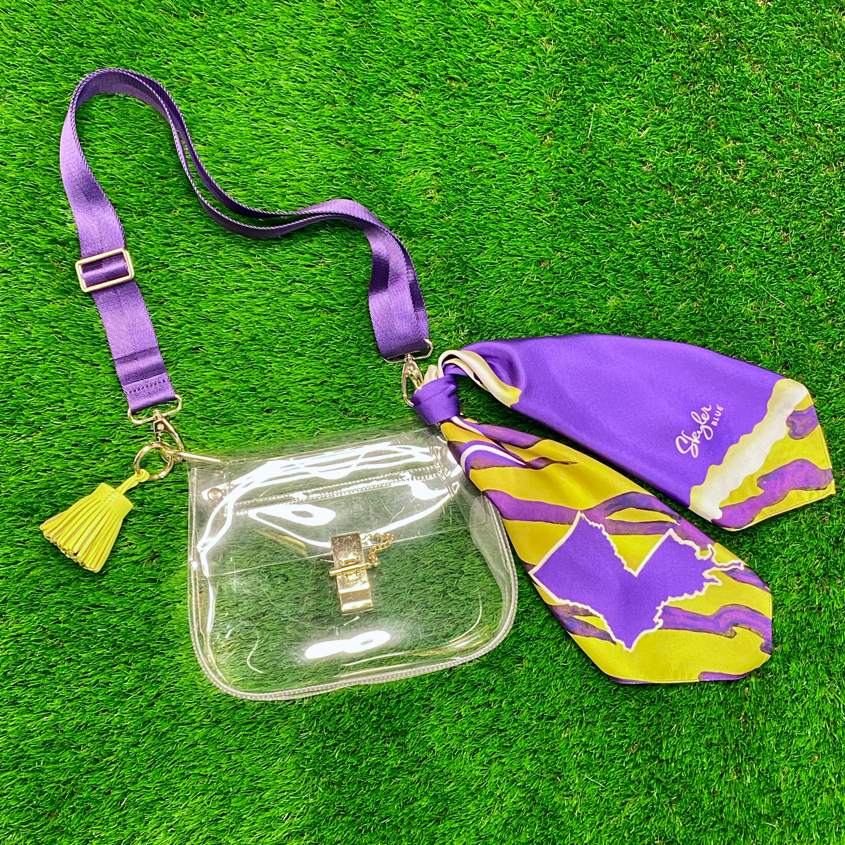 Skyler Blue’s The Baton Rouge Medium Saddle Clear Bag stadium approved clear bag / clear purse including adjustable, nylon webbing shoulder or crossbody strap with herringbone weave and gold hardware, 60-centimeter 100% silk twill scarf, and 100% genuine leather tassel.