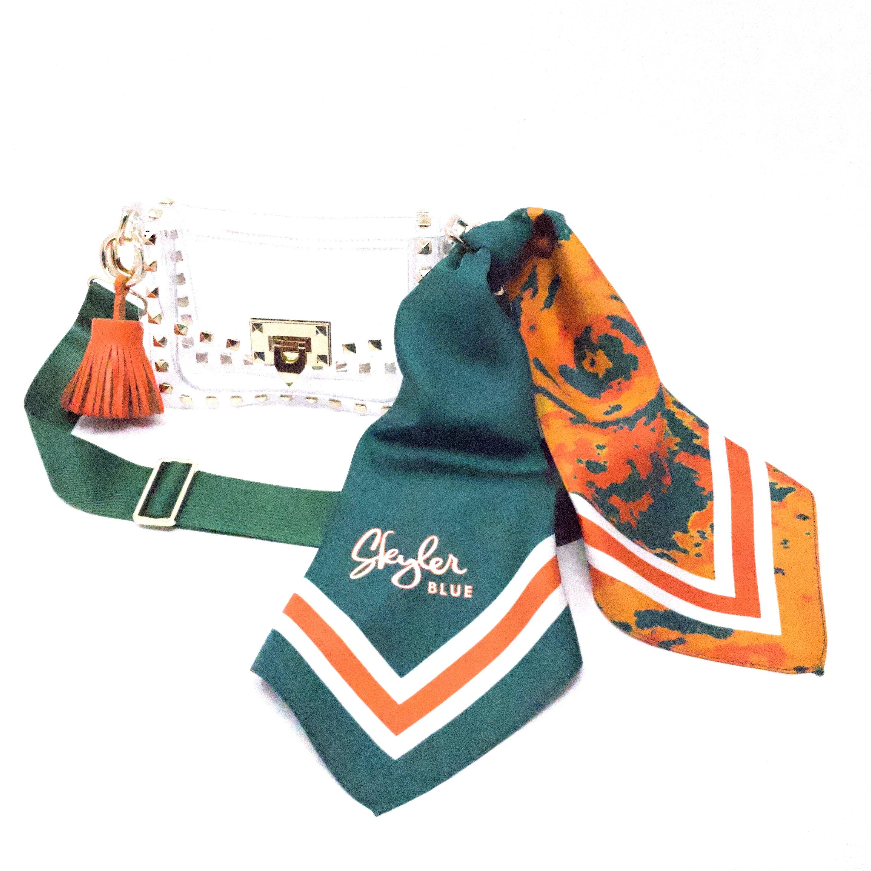 Skyler Blue’s The Coral Gables Small Studded Clear Bag stadium approved clear bag / clear purse including adjustable, nylon webbing shoulder or crossbody strap with herringbone weave and gold hardware, 60-centimeter 100% silk twill scarf, and 100% genuine leather tassel.