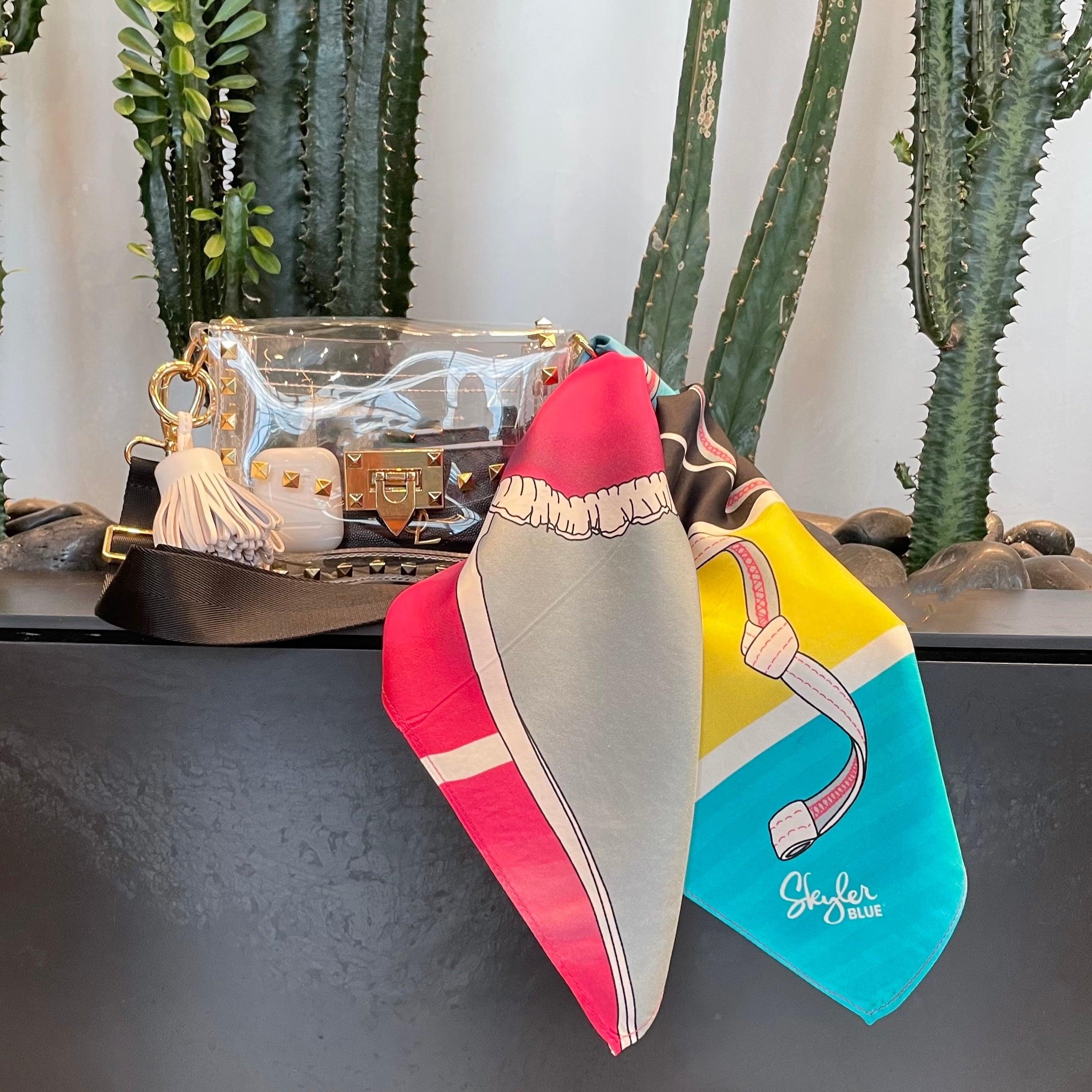 Skyler Blue’s The Bikini Small Studded Clear Bag stadium approved clear bag / clear purse including adjustable, nylon webbing shoulder or crossbody strap with herringbone weave and gold hardware, 60-centimeter 100% silk twill scarf, and 100% genuine leather tassel.
