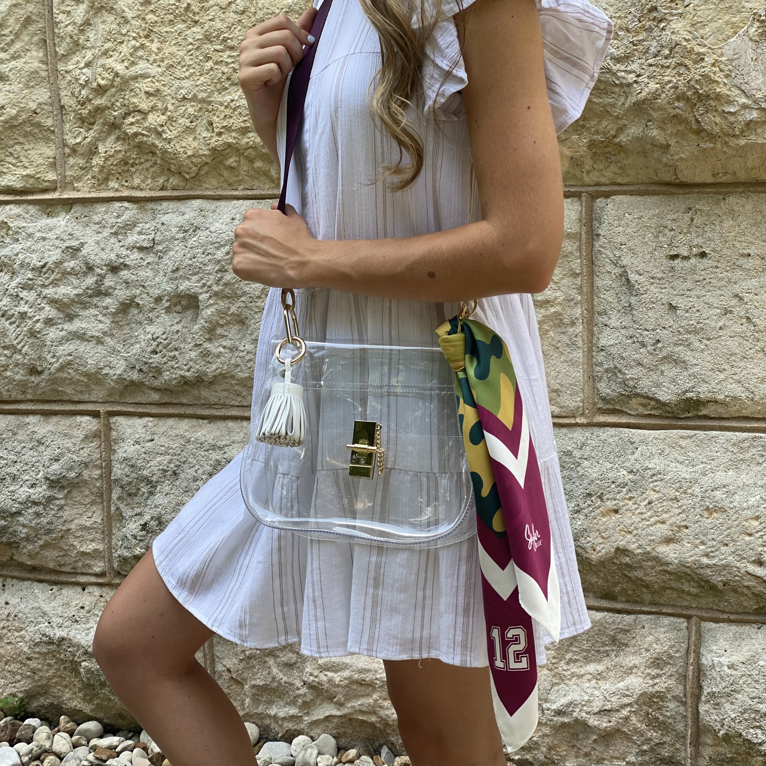 Skyler Blue’s The College Station Medium Saddle Clear Bag stadium approved clear bag / clear purse including adjustable, nylon webbing shoulder or crossbody strap with herringbone weave and gold hardware, 60-centimeter 100% silk twill scarf, and 100% genuine leather tassel. 