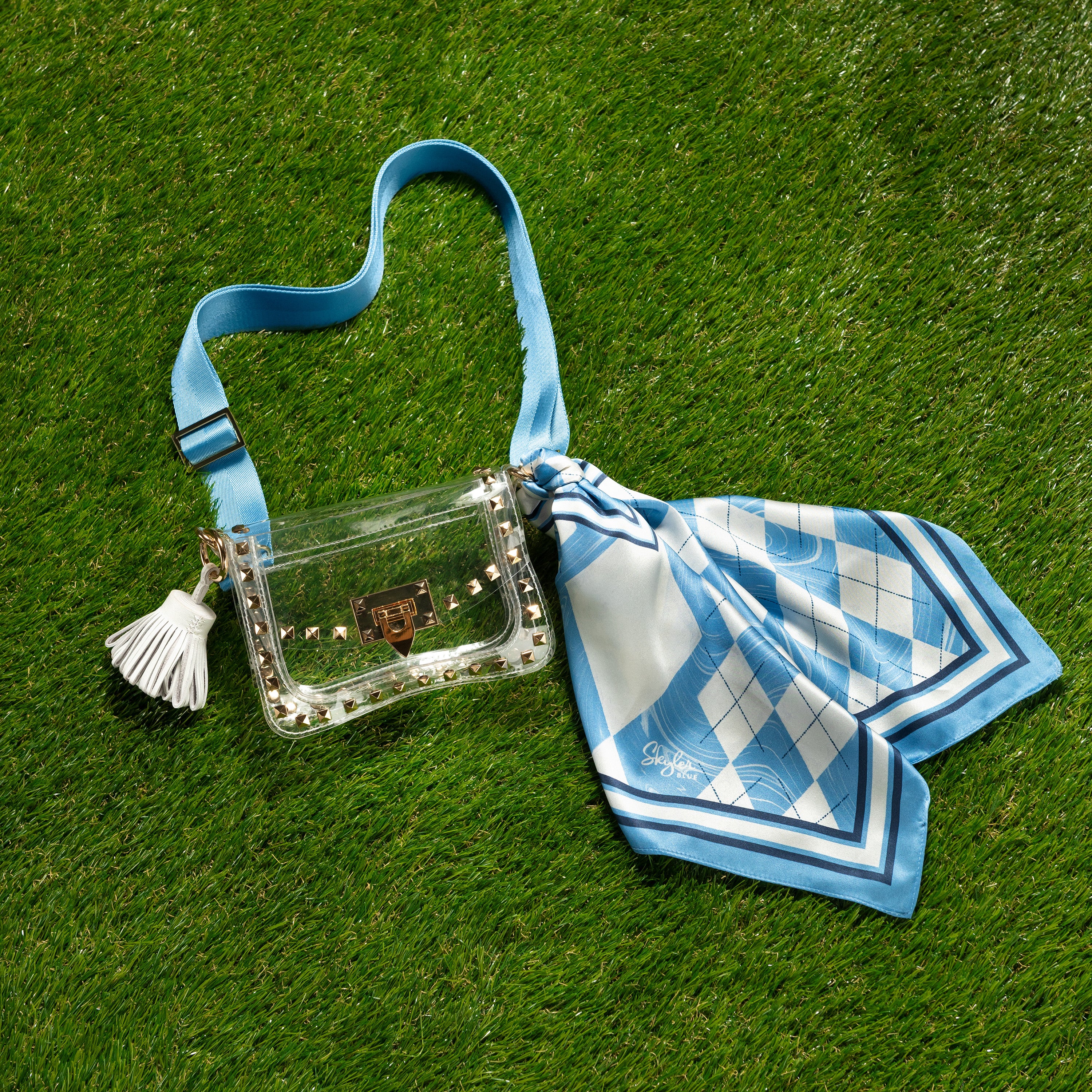 Skyler Blue’s The Chapel Hill Small Studded Clear Bag stadium approved clear bag / clear purse including adjustable, nylon webbing shoulder or crossbody strap with herringbone weave and gold hardware, 60-centimeter 100% silk twill scarf, and 100% genuine leather tassel. 