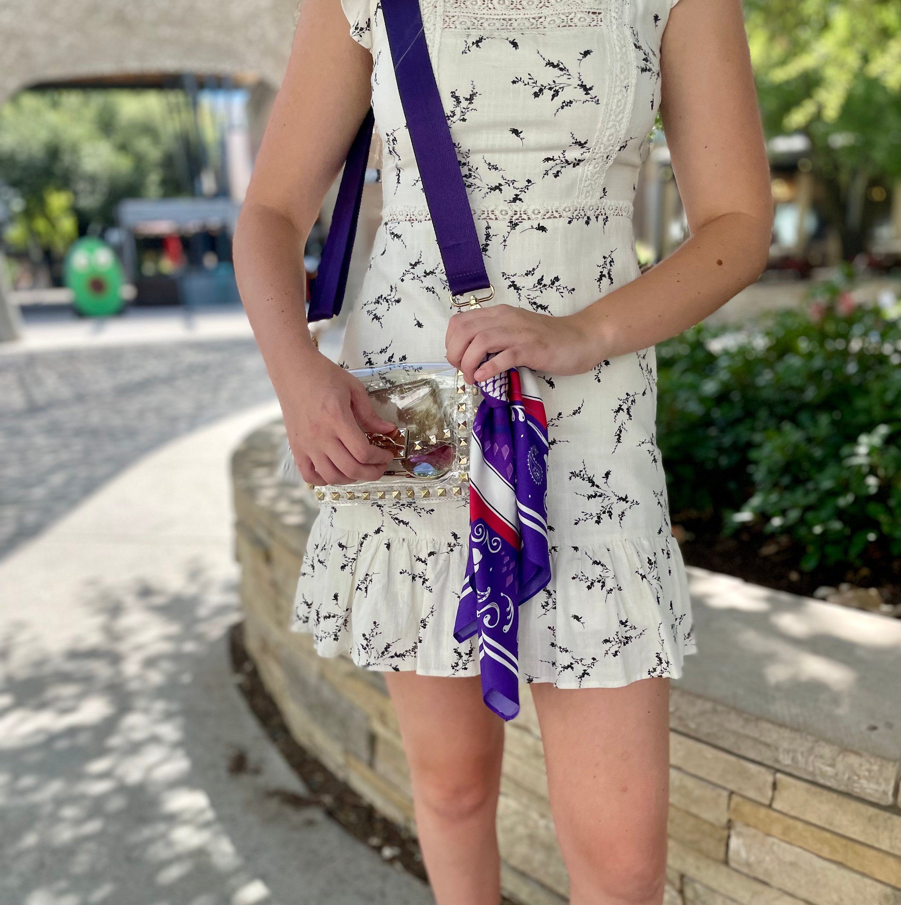 Model wearing Skyler Blue’s The Fort Worth Small Studded Clear Bag stadium approved clear bag / clear purse including adjustable, nylon webbing shoulder or crossbody strap with herringbone weave and gold hardware, 60-centimeter 100% silk twill scarf, and 100% genuine leather tassel. 