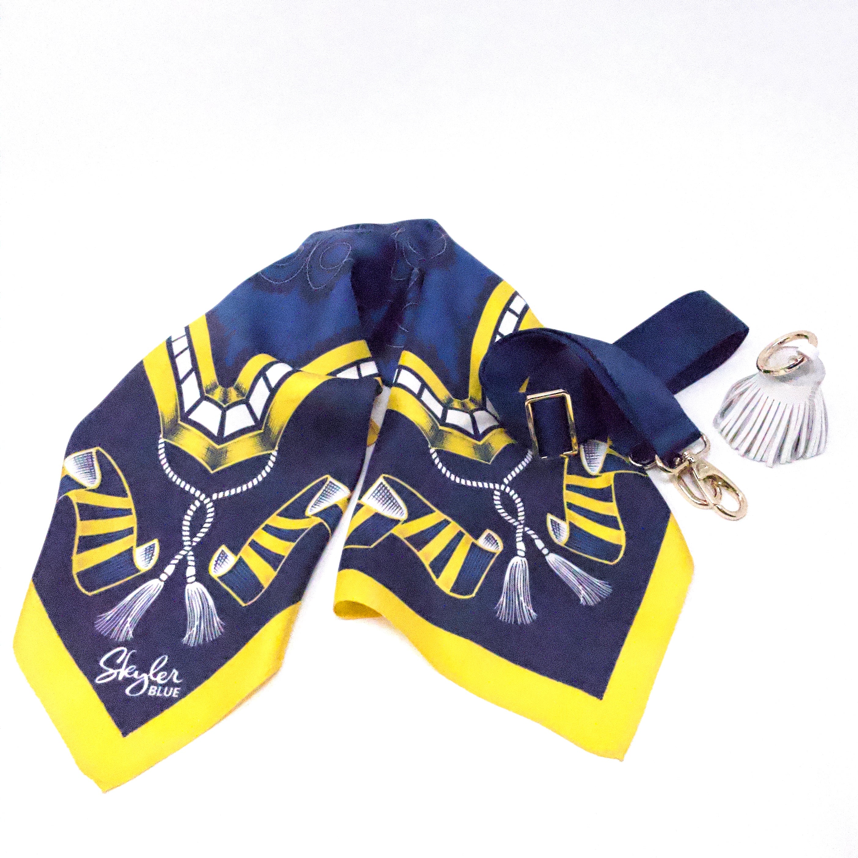 Skyler Blue’s The Ann Arbor Accessory Package including adjustable, nylon webbing shoulder or crossbody strap with herringbone weave and gold hardware, 60-centimeter 100% silk twill scarf, and 100% genuine leather tassel. 