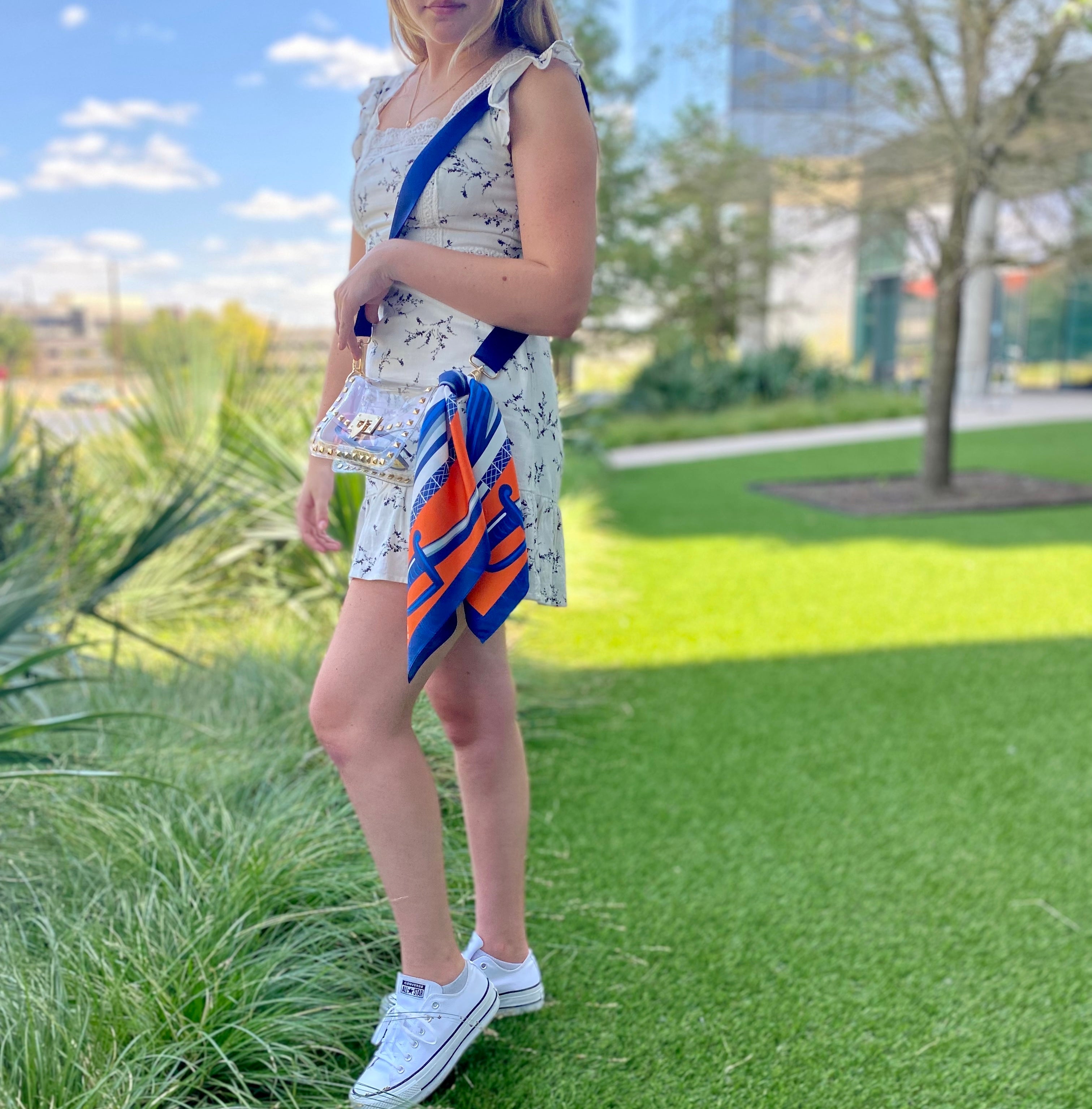 Model wearing Skyler Blue’s The Charlottesville Small Studded Clear Bag stadium approved clear bag / clear purse including adjustable, nylon webbing shoulder or crossbody strap with herringbone weave and gold hardware, 60-centimeter 100% silk twill scarf, and 100% genuine leather tassel. 