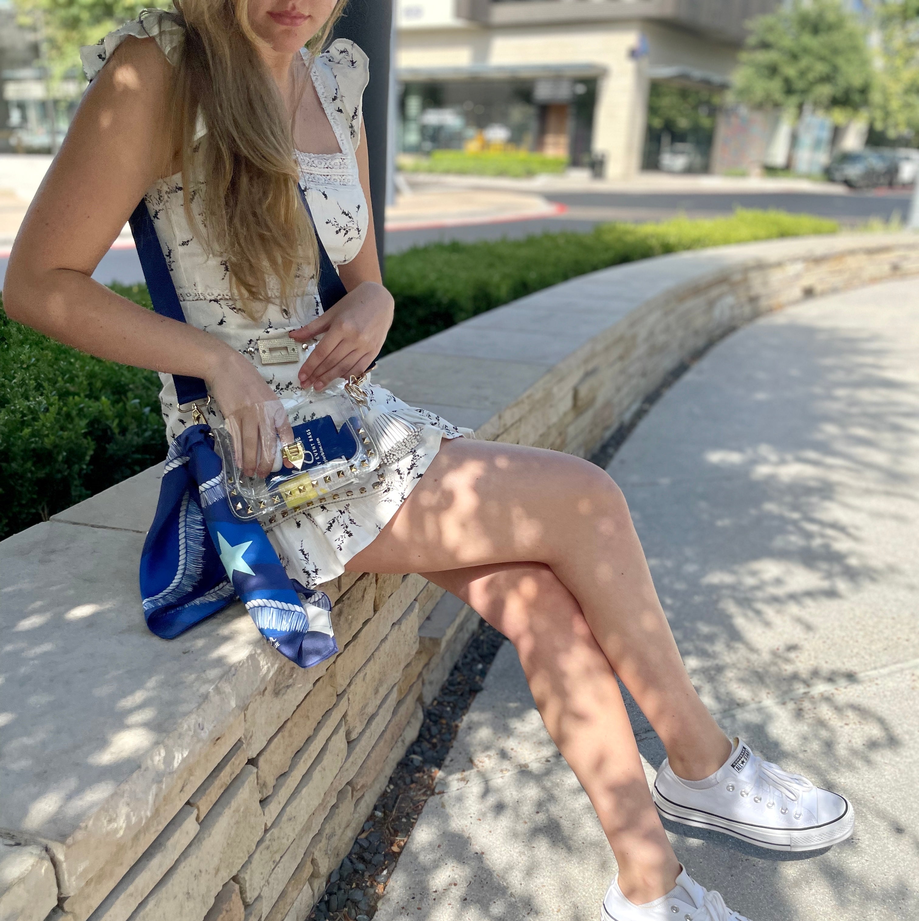Model wearing Skyler Blue’s The Dallas 002 Small Studded Clear Bag stadium approved clear bag / clear purse including adjustable, nylon webbing shoulder or crossbody strap with herringbone weave and gold hardware, 60-centimeter 100% silk twill scarf, and 100% genuine leather tassel. 