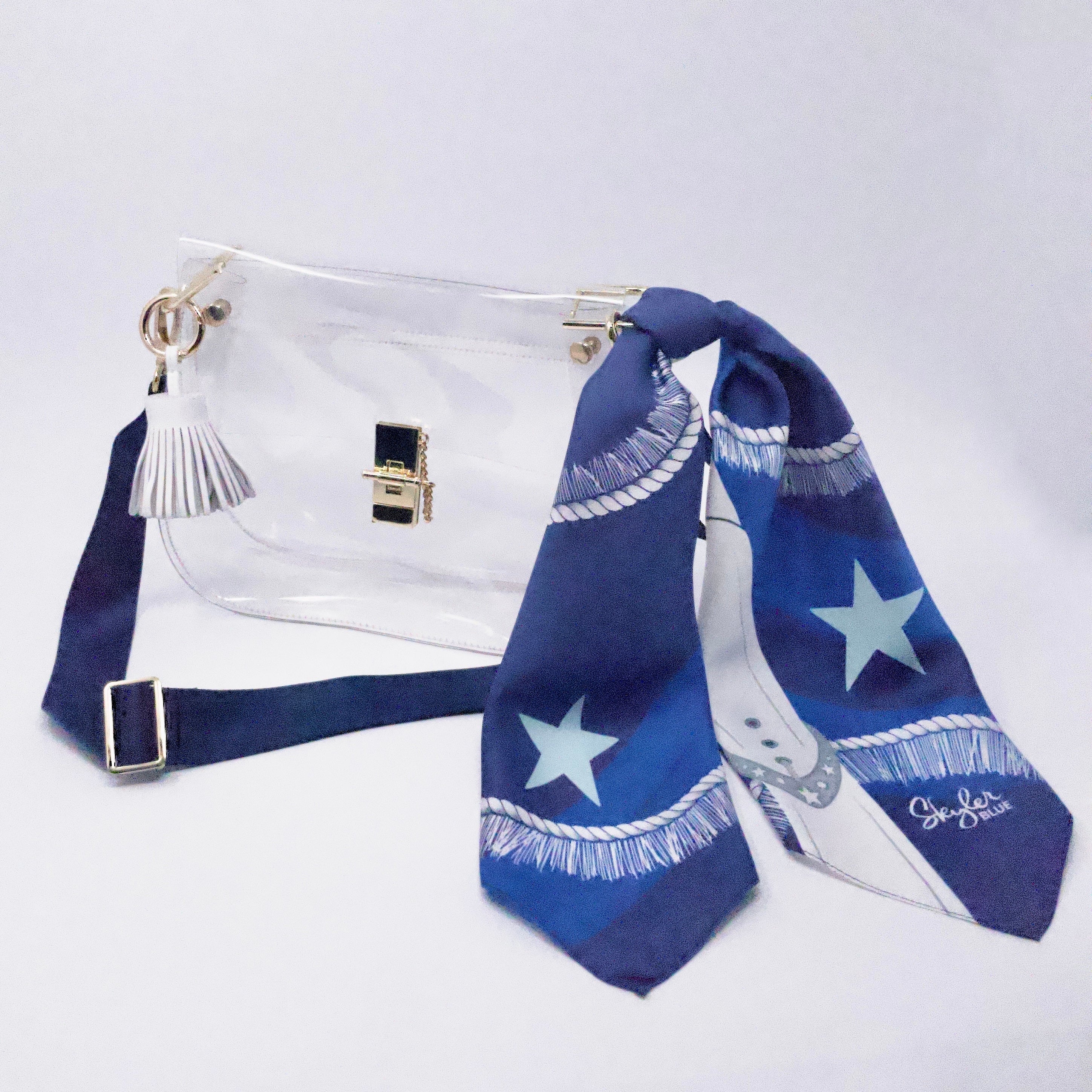 Skyler Blue’s The Dallas 002 Medium Saddle Clear Bag stadium approved clear bag / clear purse including adjustable, nylon webbing shoulder or crossbody strap with herringbone weave and gold hardware, 60-centimeter 100% silk twill scarf, and 100% genuine leather tassel. 