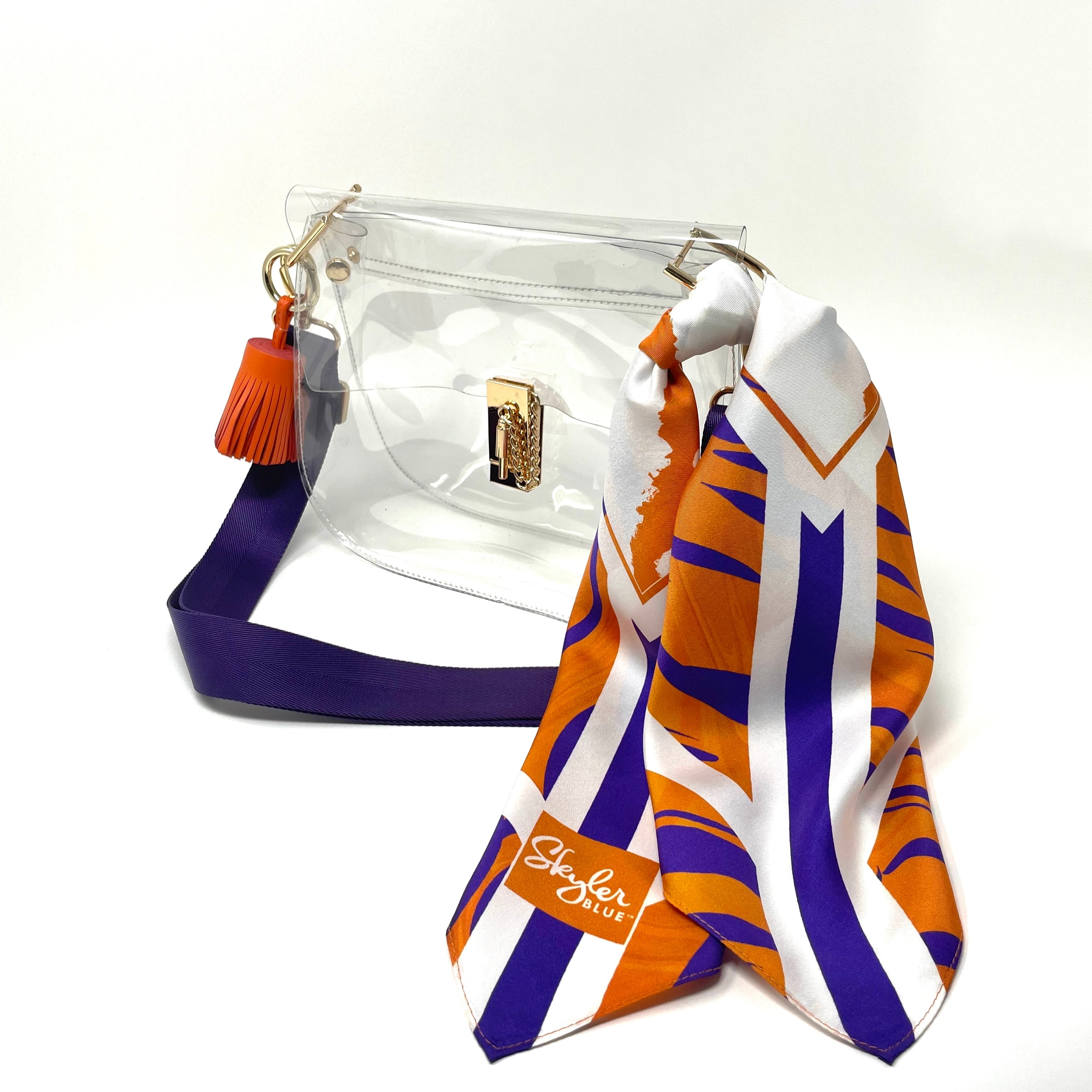 Skyler Blue’s The Howard Medium Saddle Clear Bag stadium approved clear bag / clear purse including adjustable, nylon webbing shoulder or crossbody strap with herringbone weave and gold hardware, 60-centimeter 100% silk twill scarf, and 100% genuine leather tassel. 