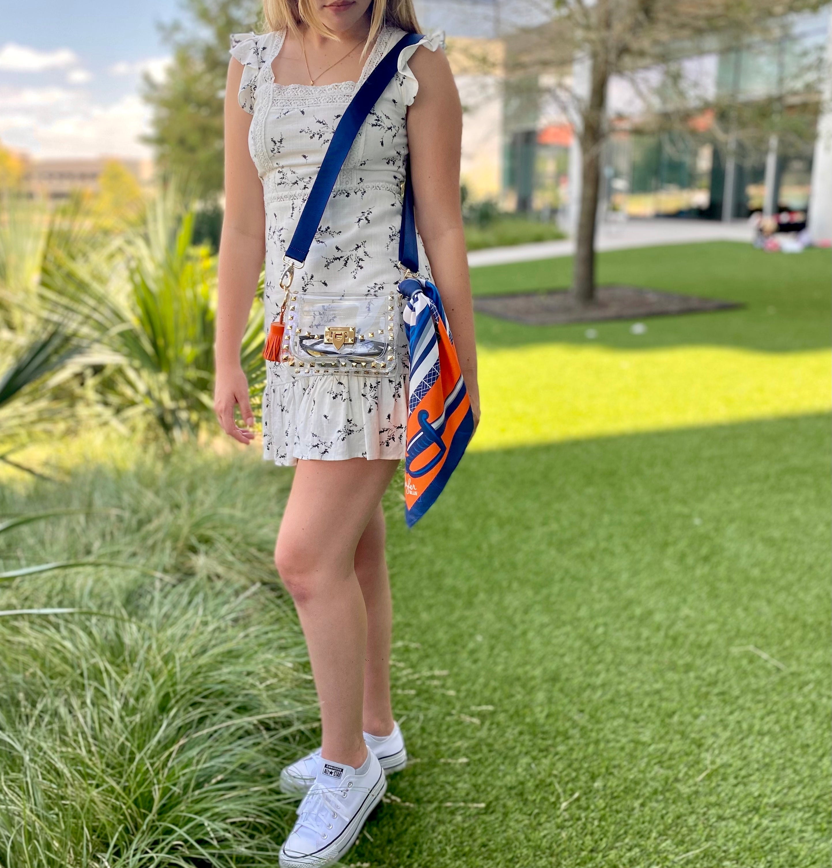 Model wearing Skyler Blue’s The Charlottesville Small Studded Clear Bag stadium approved clear bag / clear purse including adjustable, nylon webbing shoulder or crossbody strap with herringbone weave and gold hardware, 60-centimeter 100% silk twill scarf, and 100% genuine leather tassel. 
