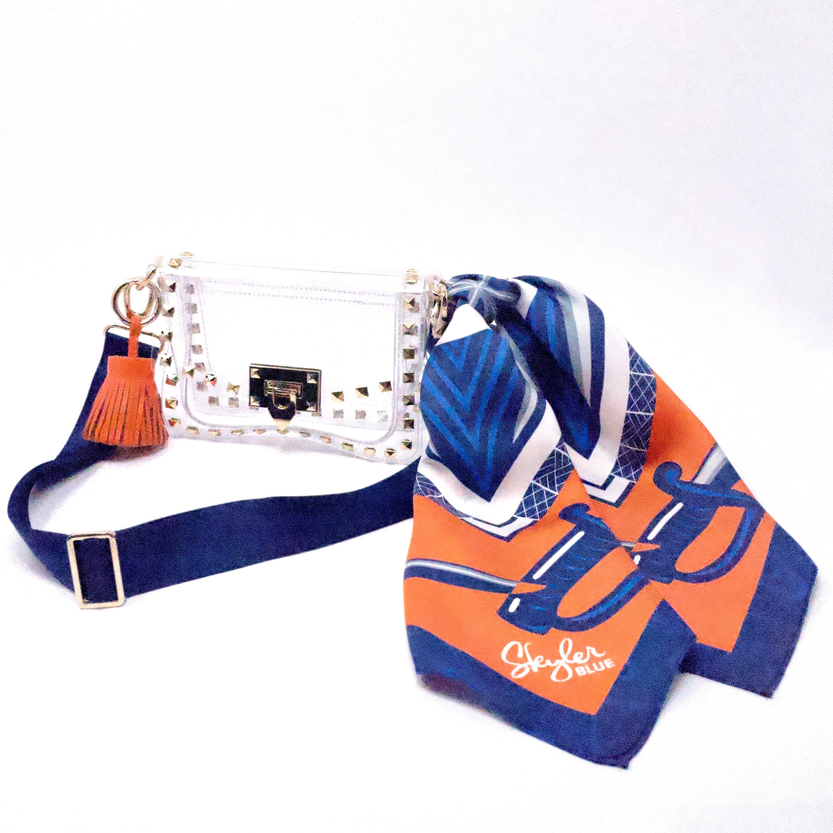 Skyler Blue’s The Charlottesville Small Studded Clear Bag stadium approved clear bag / clear purse including adjustable, nylon webbing shoulder or crossbody strap with herringbone weave and gold hardware, 60-centimeter 100% silk twill scarf, and 100% genuine leather tassel. 