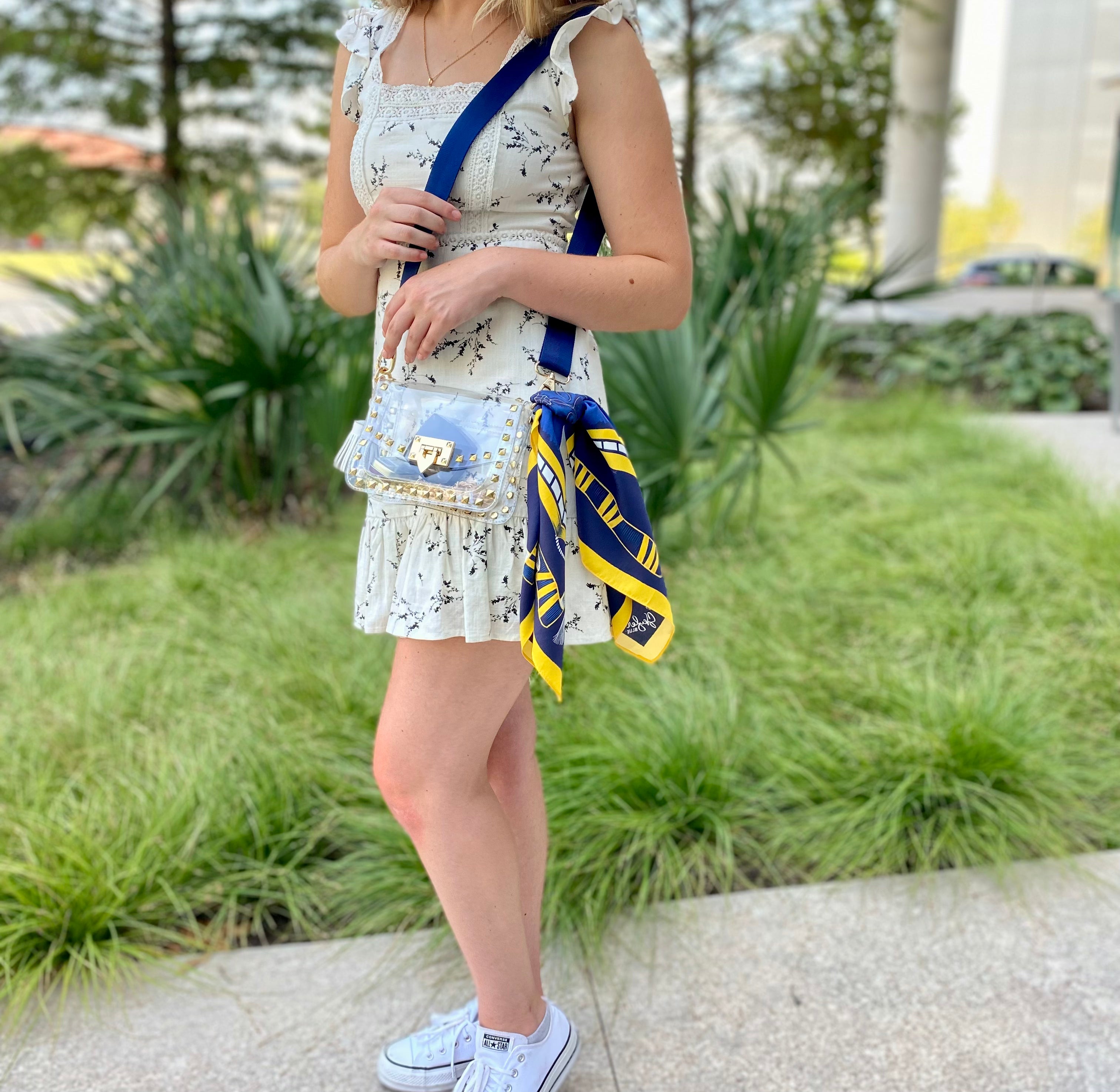 Model wearing Skyler Blue’s The Ann Arbor Small Studded Clear Bag stadium approved clear bag / clear purse including adjustable, nylon webbing shoulder or crossbody strap with herringbone weave and gold hardware, 60-centimeter 100% silk twill scarf, and 100% genuine leather tassel. 